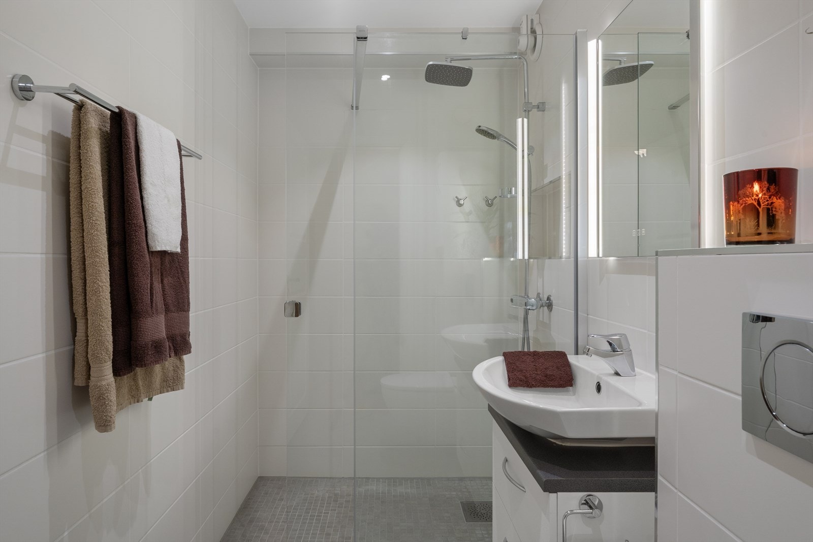 Badet er utstyrt med dusjhjørne med glassvegger og vegghengt toalett. Galleribilde