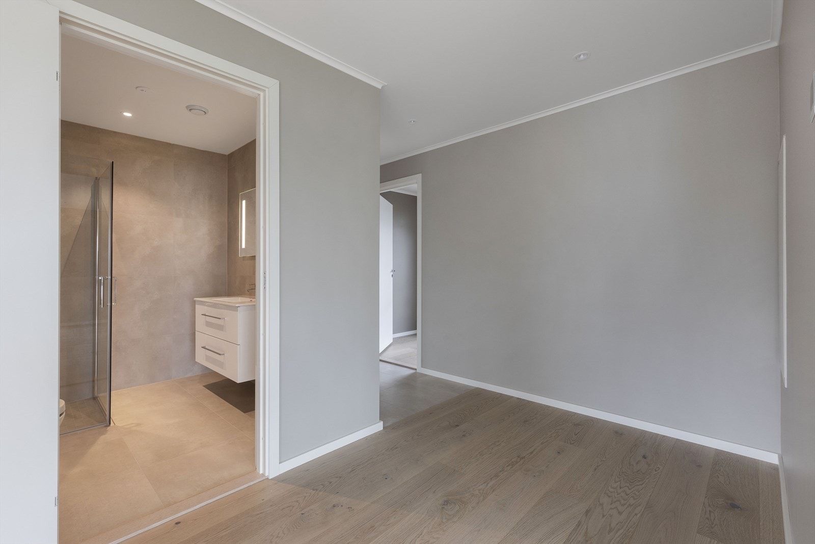 Badet med vaskeromsfunksjon har flislagte gulv og vegger, downlights i malt himling og gulvvarme. Galleribilde