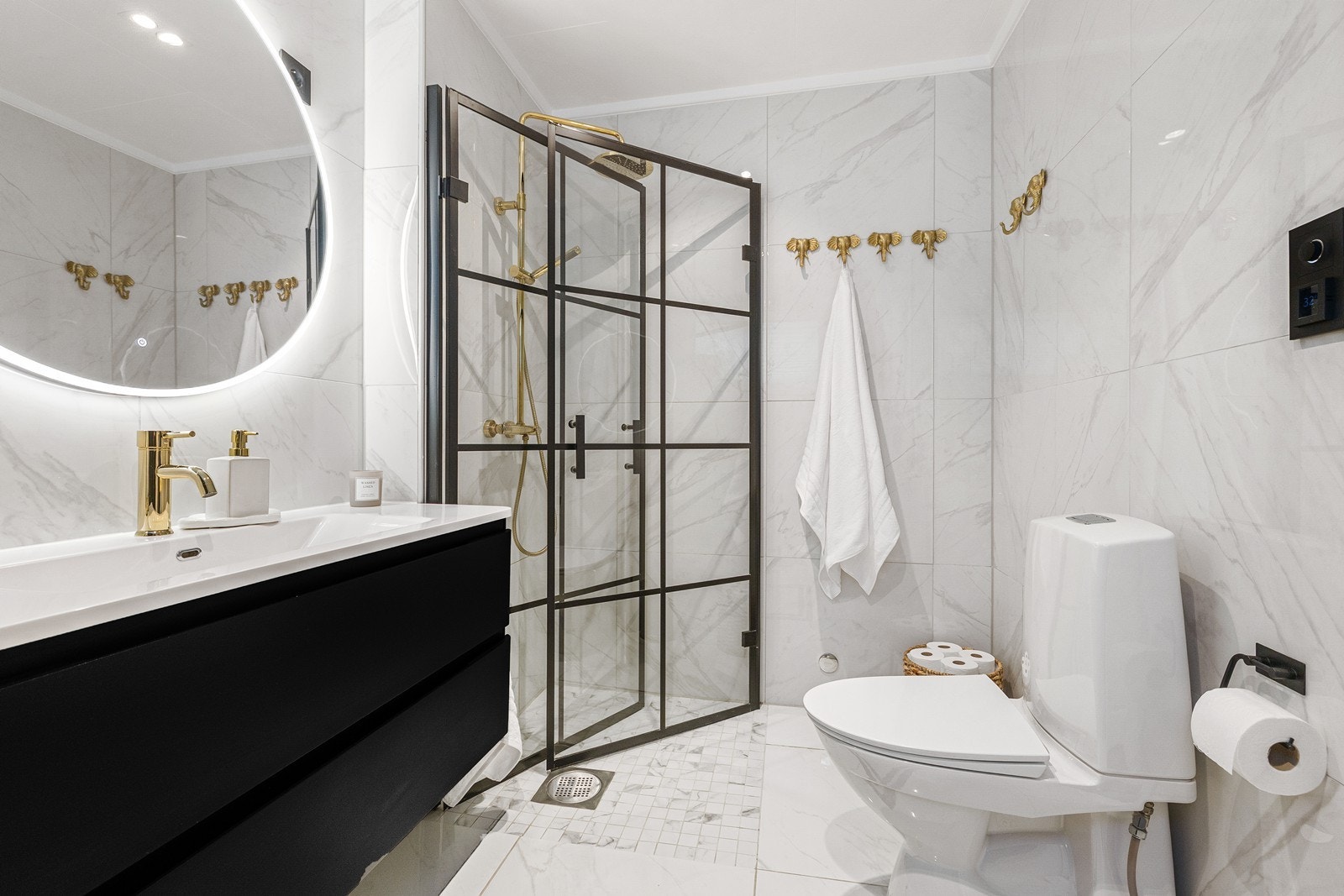Badet er innredet med servant i baderomsinnredning, speil med bakgrunnsbelysning, toalett og dusjhjørne med innfellbare glassvegger. Galleribilde
