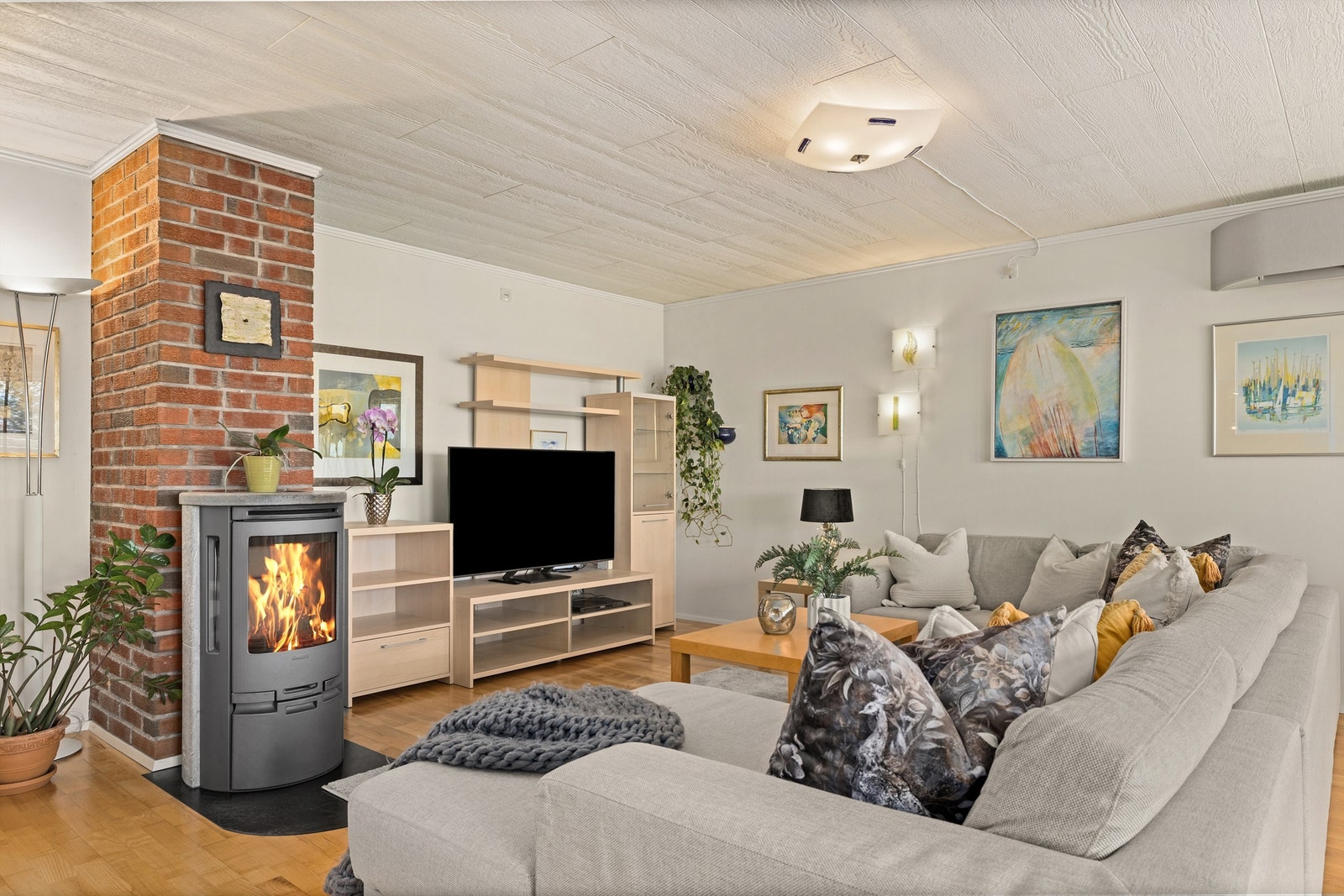 En teglsteinspipe gir karakter til rommet, og vedovnen bidrar med både varme og hygge. Galleribilde