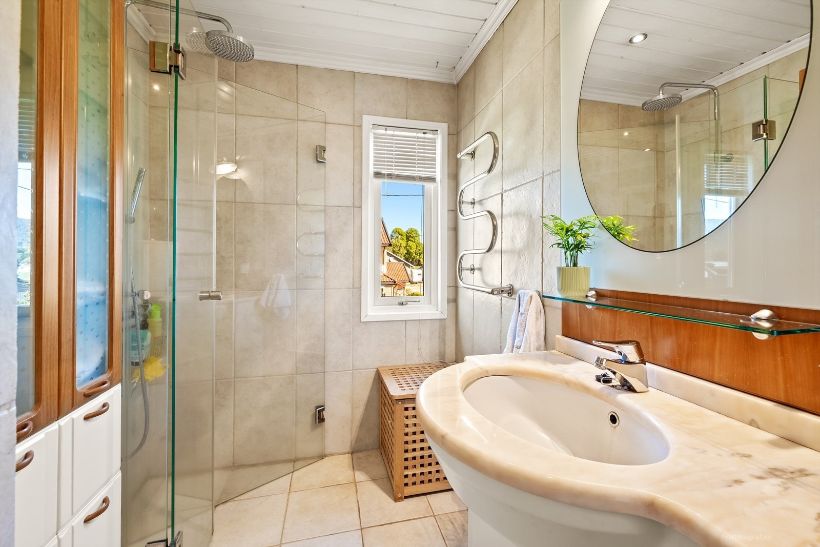 Badet er innredet med dusjhjørne med glassvegger, veggmontert toalett og servant. Galleribilde
