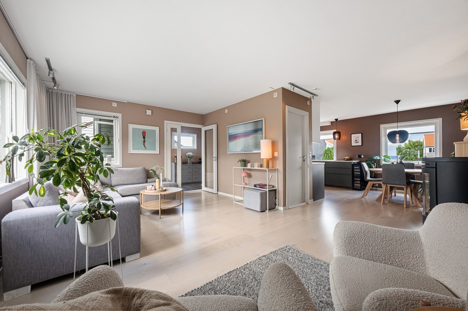 Lys og romslig stue med store vinduer som slipper inn rikelig med naturlig lys. Delvis åpen løsning mellom stue og kjøkken. Galleribilde