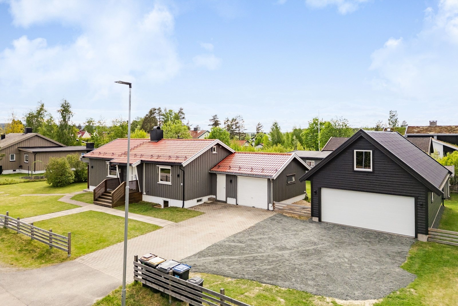 En stor og solrik eiendom som er bebygd med en godt vedlikeholdt enebolig med inntilbygget garasje og lagerrom, stor dobbelgarasje fra 2022 og en lekestue. Galleribilde