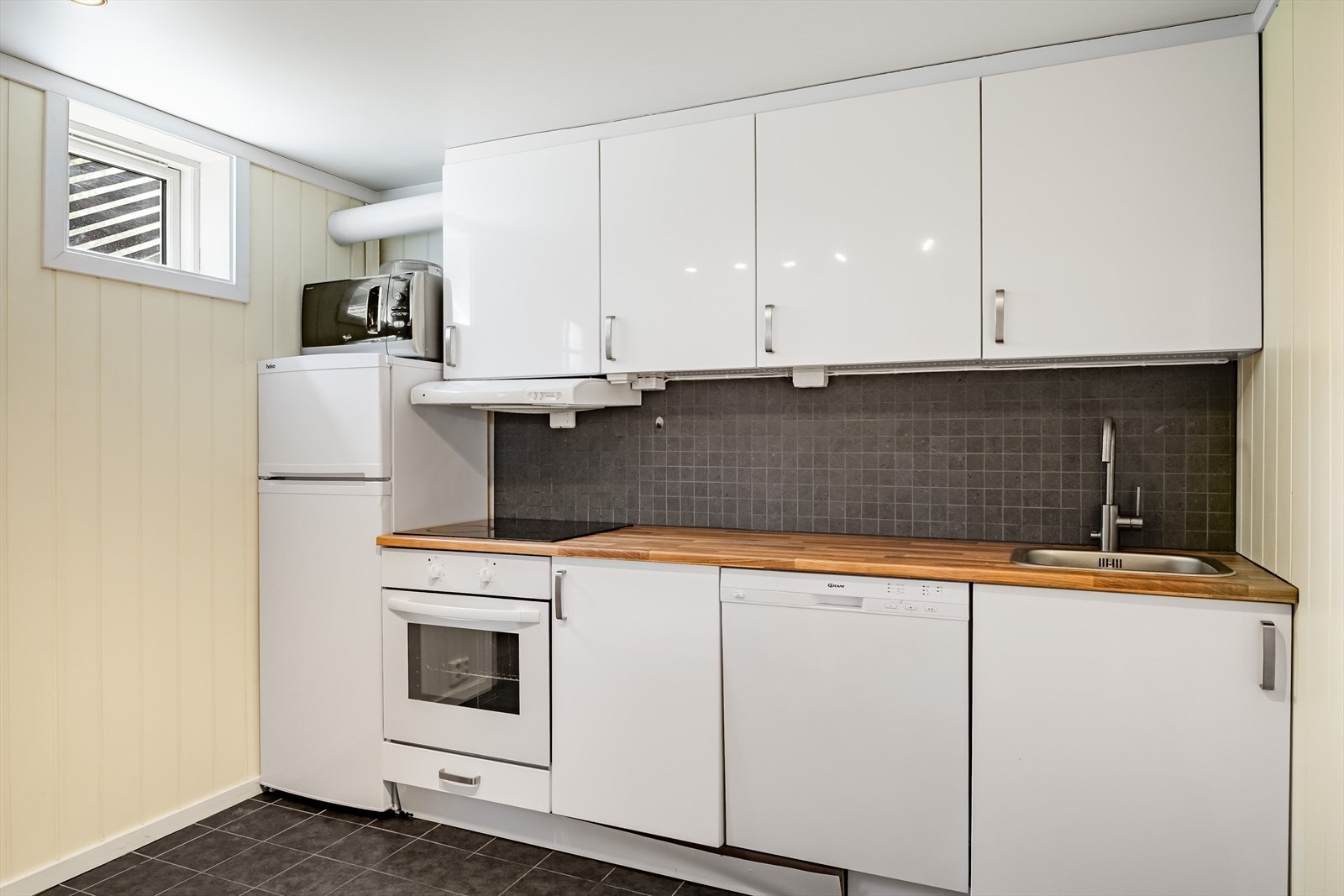 Lys kjøkkeninnredning med glatte fronter og laminert benkeplate med nedfelt oppvaskkum. Galleribilde