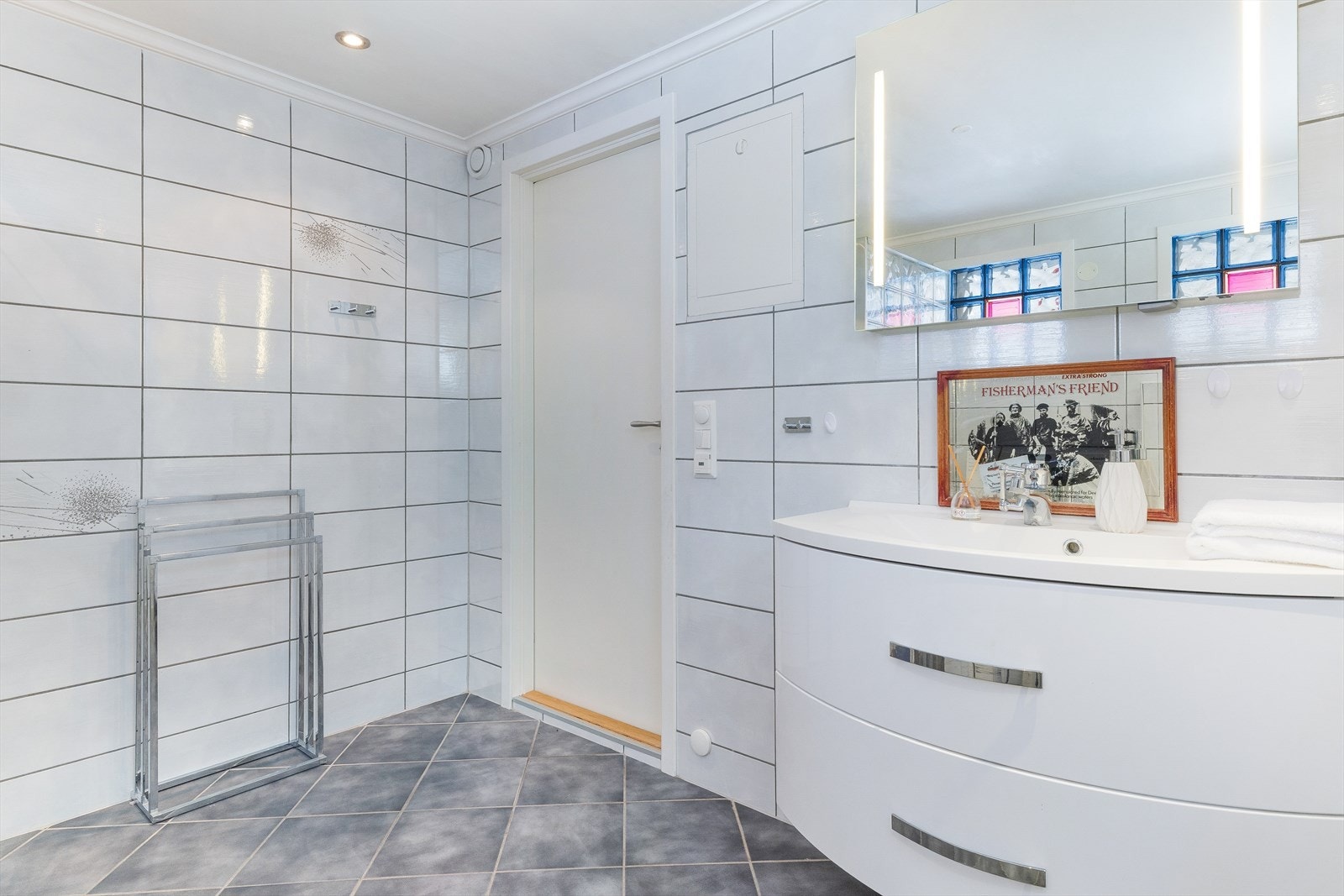 Pent flislagt bad med moderne uttrykk og praktisk løsning. Gode lysforhold og funksjonell planløsning gjør rommet både komfortabelt og lettstelt. Galleribilde