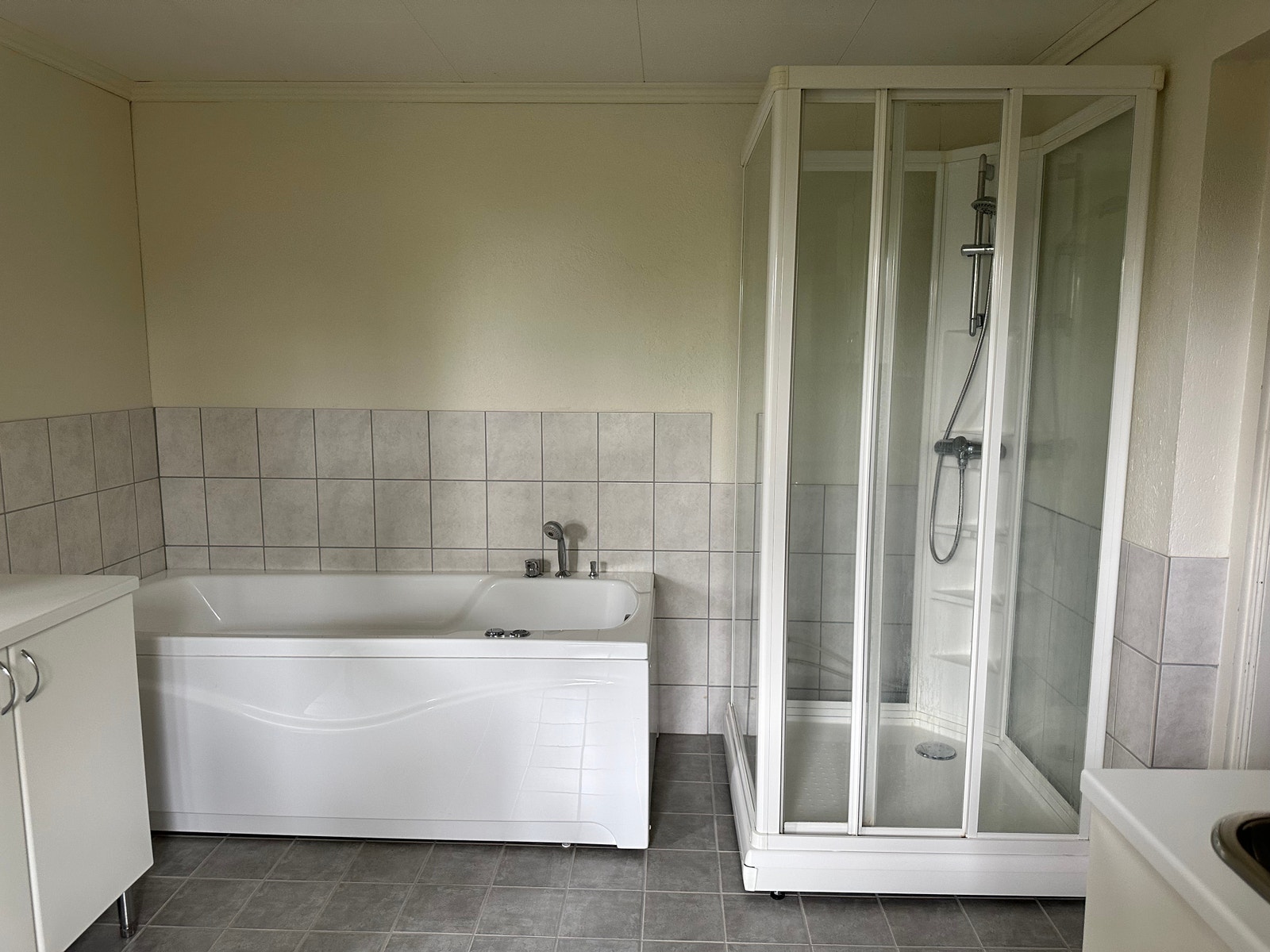 Bad med dusj, badekar, vaskemaskin og tørketrommer i underetasjen Galleribilde