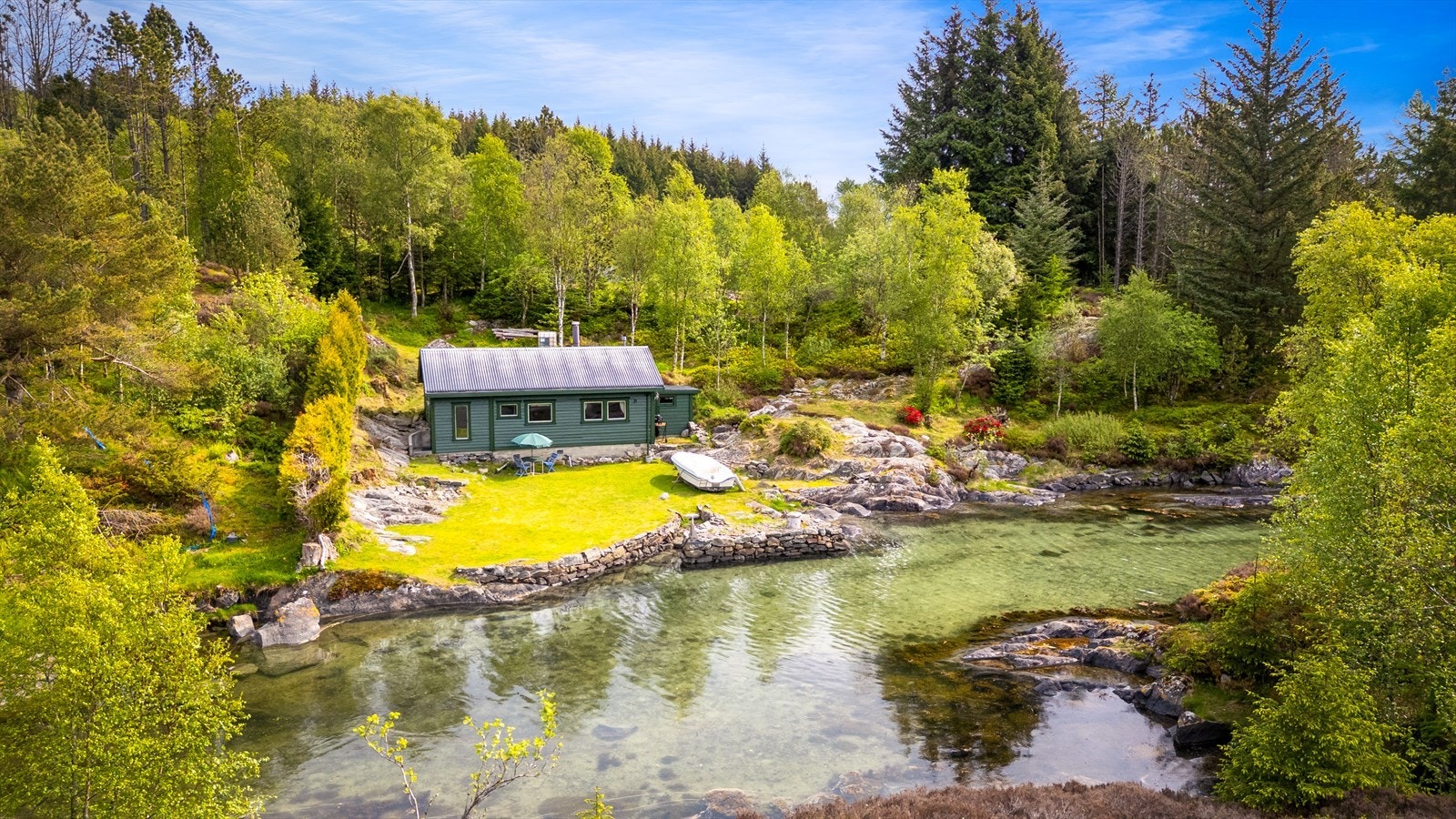 Hytta ligger lunt til i en liten vik, skjermet av terrenget. Galleribilde