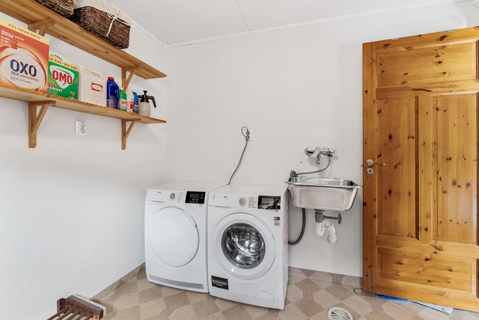 Praktisk vaskerom med opplegg for vaskemaskin og skyllekar på vegg. Galleribilde