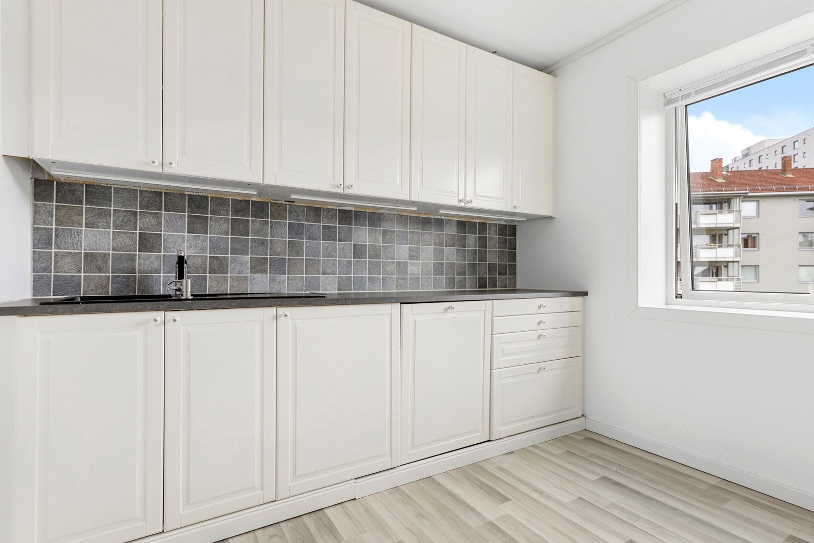 Kjøkkeninnredning fra IKEA med profilerte fronter, det er integerert vaskemaskin og frittstående stekeovn og kjøl/fryseskap. Det er plass til et hyggelig lite spisebord Galleribilde