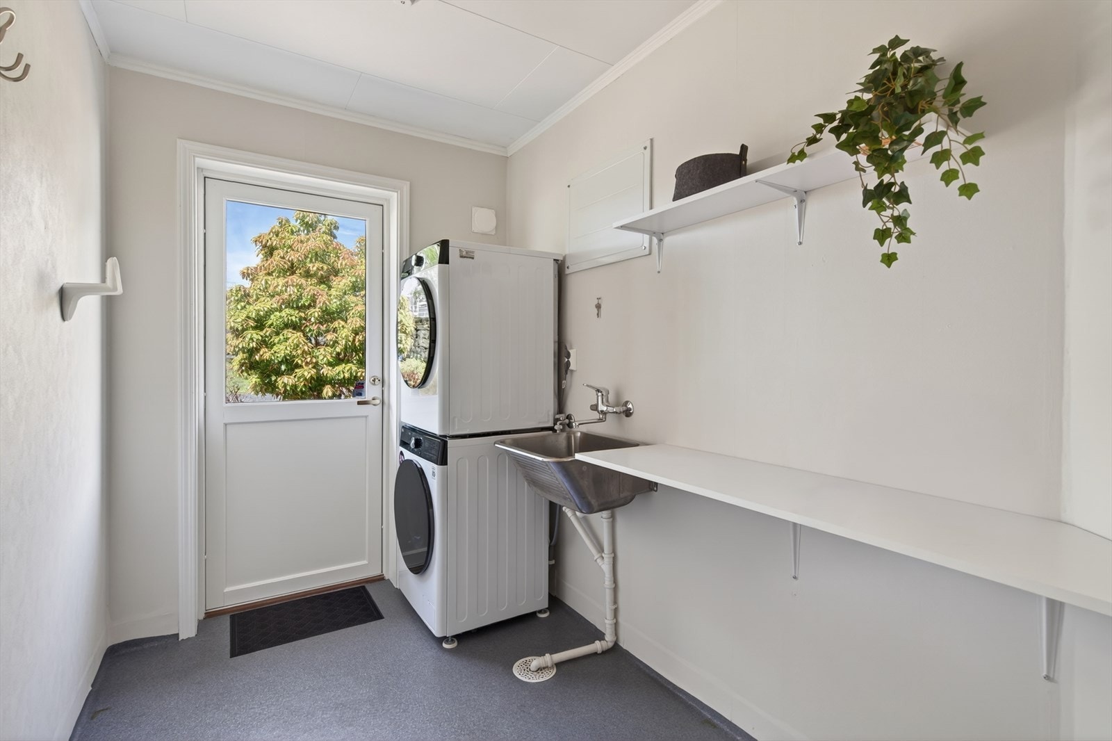 Praktisk vaskerom med opplegg for vaskemaskin og tørketrommel, samt utgang til en nordvestvendt terrasse. Galleribilde
