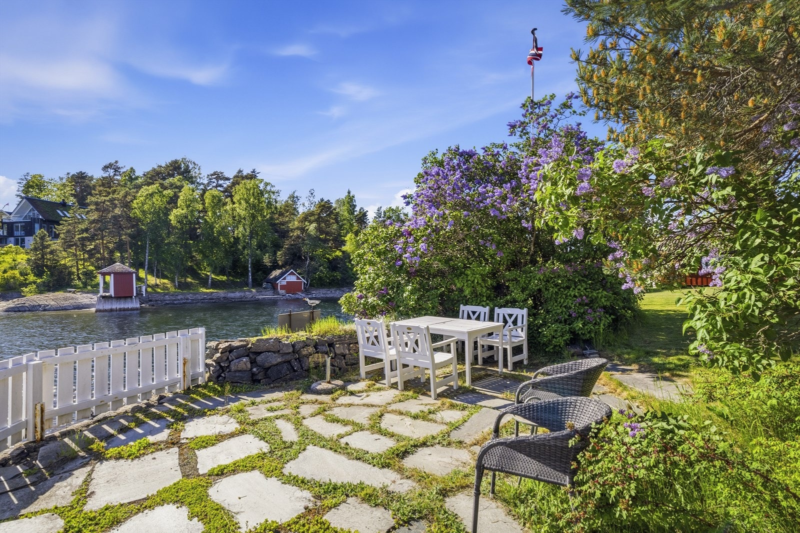 En steinbelagt uteplass i hagen, rammet inn av en solid steinmur mot sjøen. Galleribilde