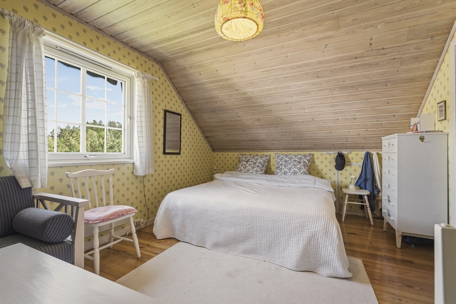 Soverom i andre etasje med sjarmerende skråtak og panel i himling. Galleribilde