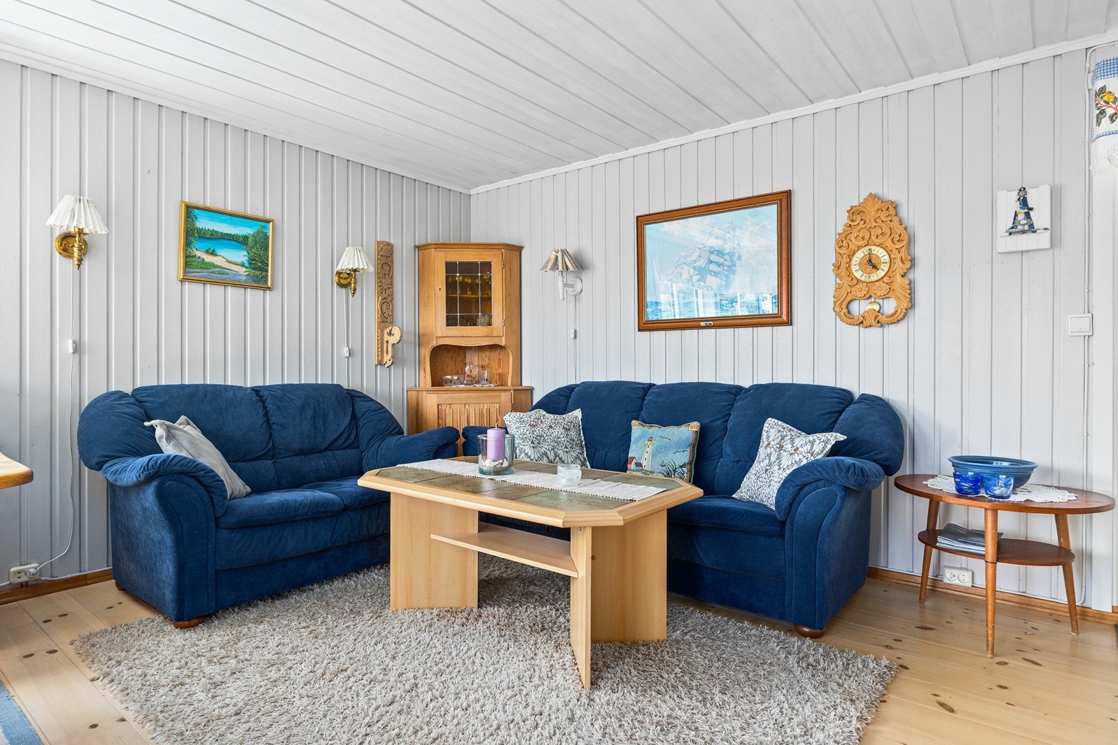 Stuen har plass til en romslig sofagruppe. Overflatene består av tregulv og malt panel på vegger og i himling. Galleribilde