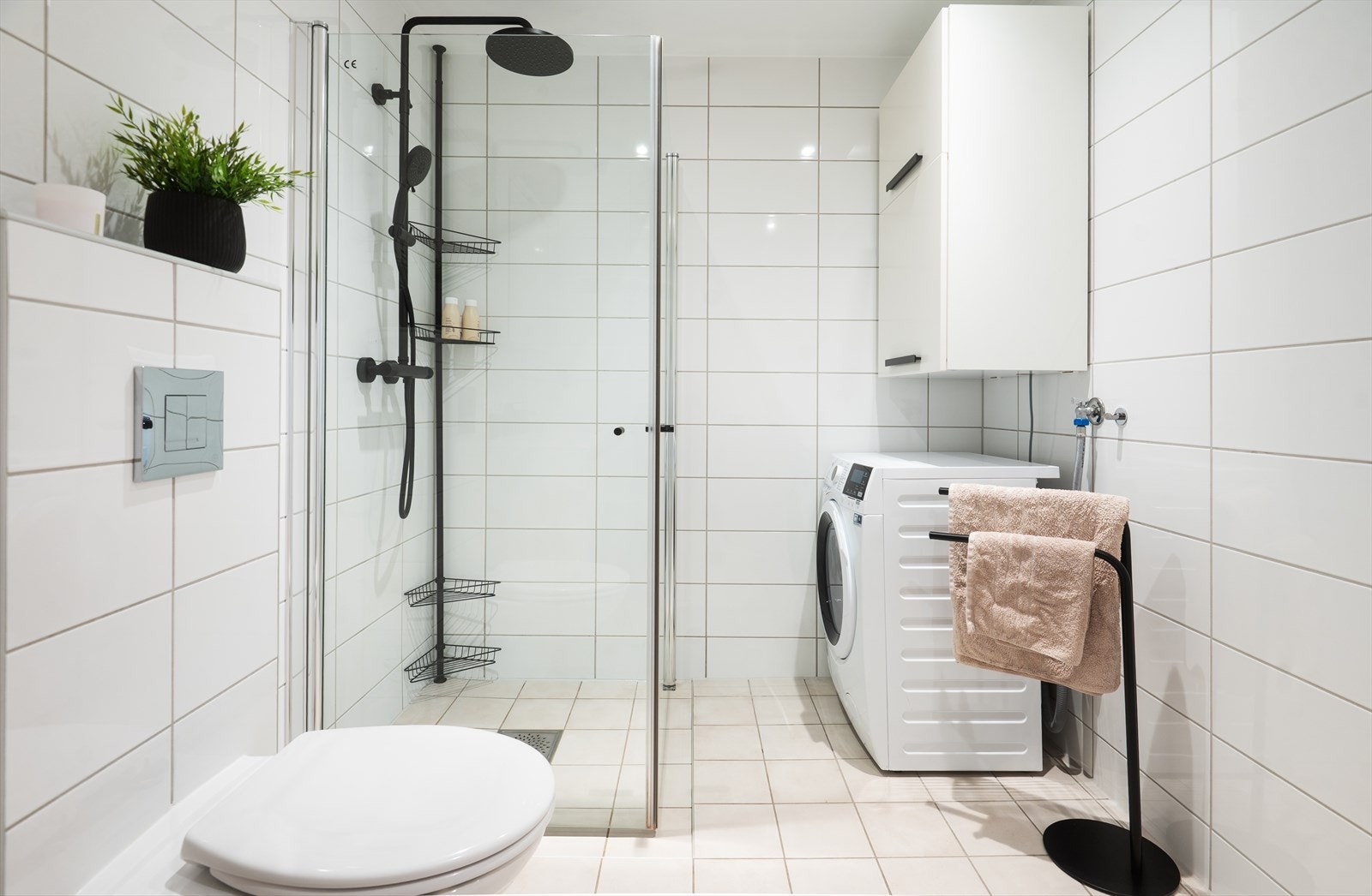 Badet er utstyrt med vegghengt toalett, innredning med servant, speilskap, dusjhjørne og opplegg for vaskemaskin. Galleribilde
