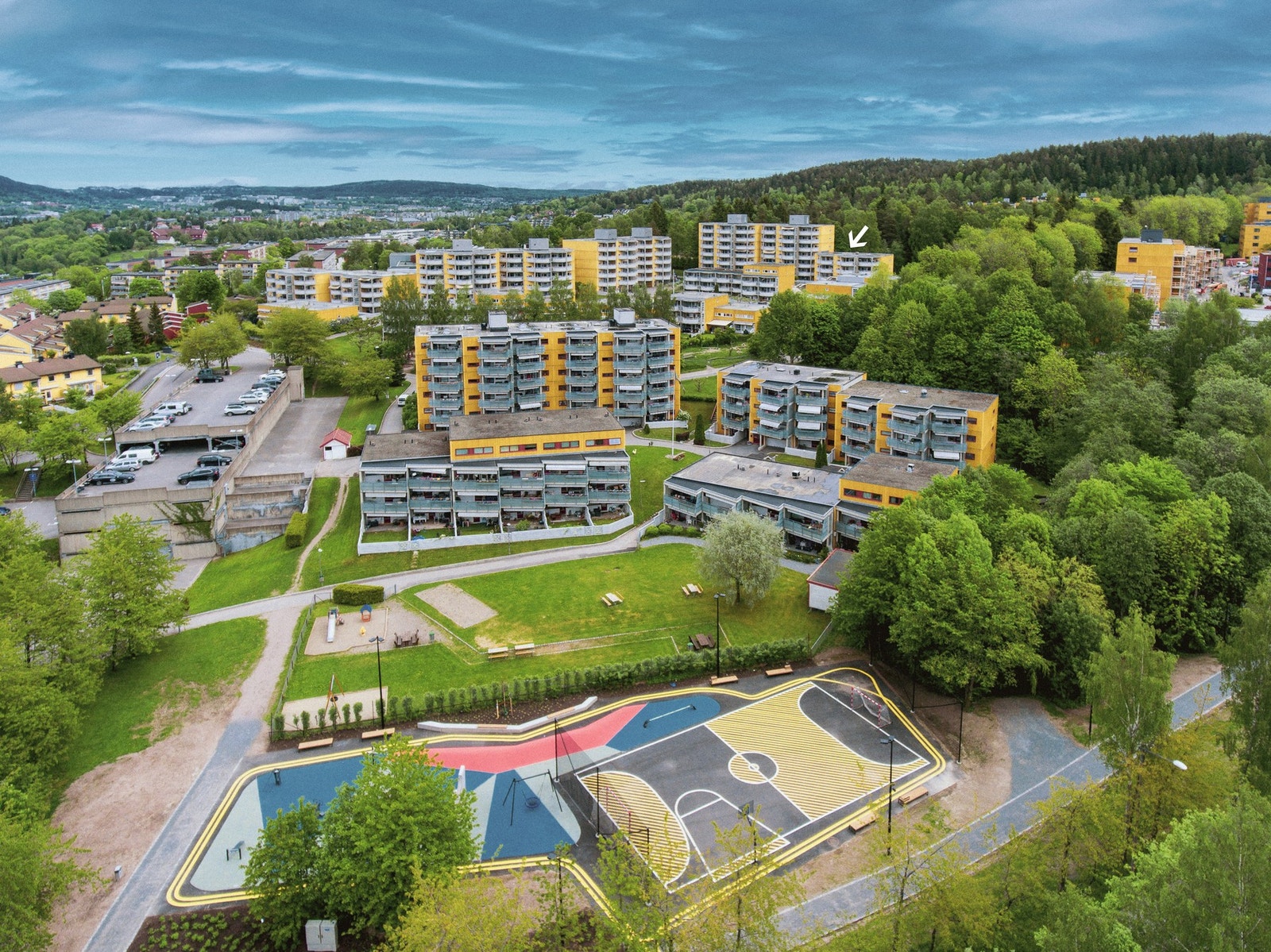 Det er mulighet for å leie parkeringsplass eller garasjeplass ved innkjøringen til borettslaget. Garasjehuset vises til venstre i bildet. Galleribilde