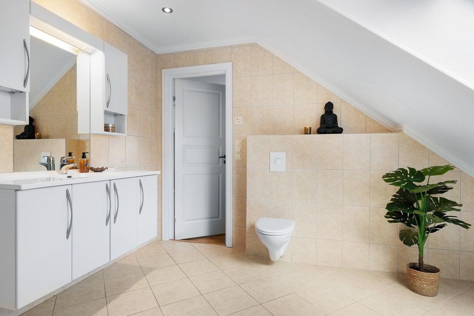 Badet har flislagt gulv med vannbåren varme og vegghengt toalett. Galleribilde