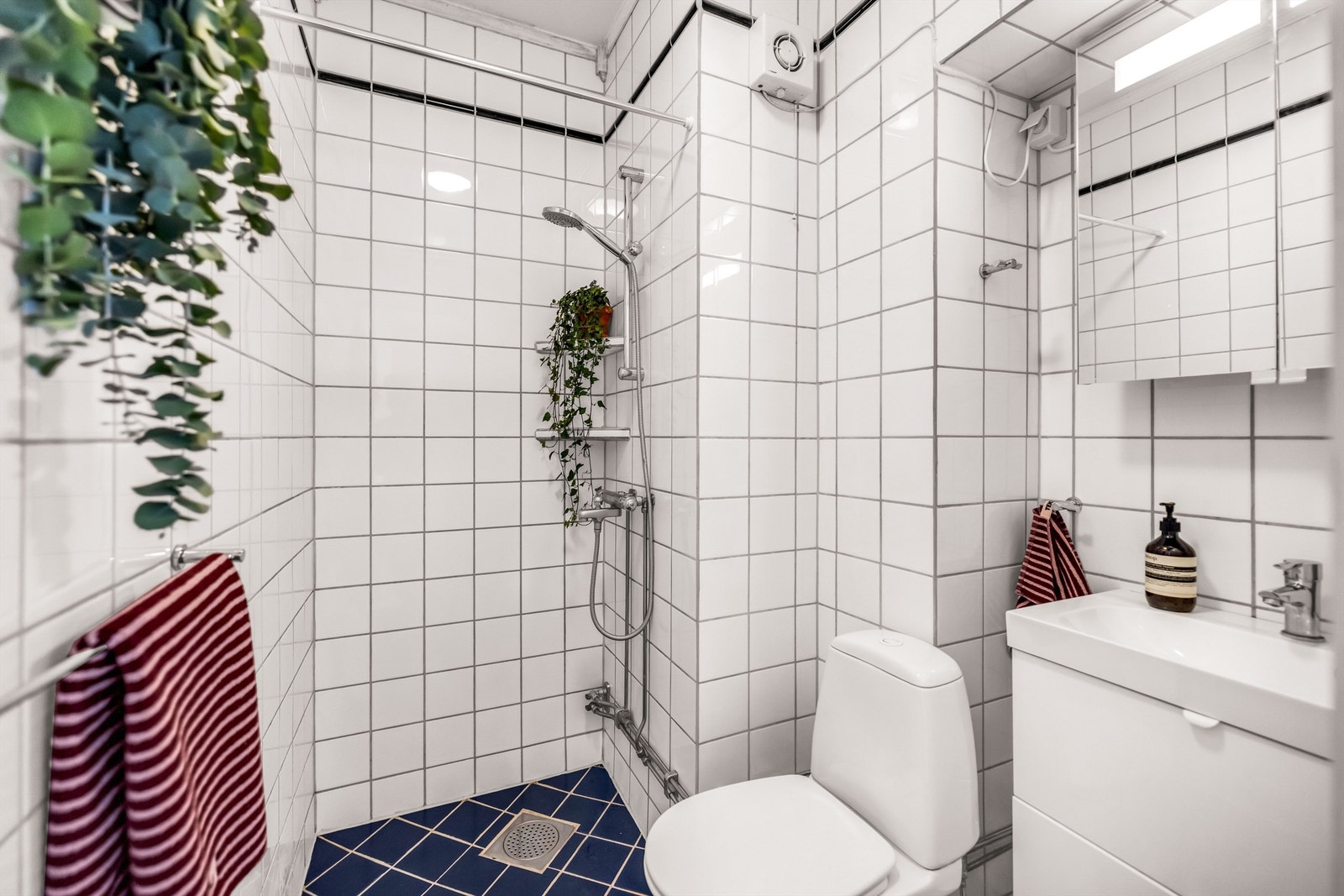 Badet er innredet med gulvstående toalett og dusjsone med dusjforheng som er tilkoblet hånddusj. Galleribilde
