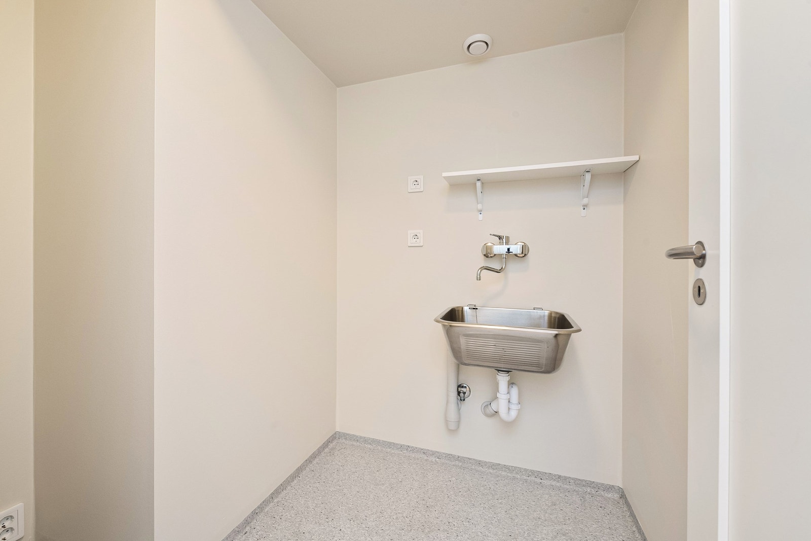Praktisk vaskerom med gulvvarme, utslagsvask og opplegg for vaskemaskin. Galleribilde