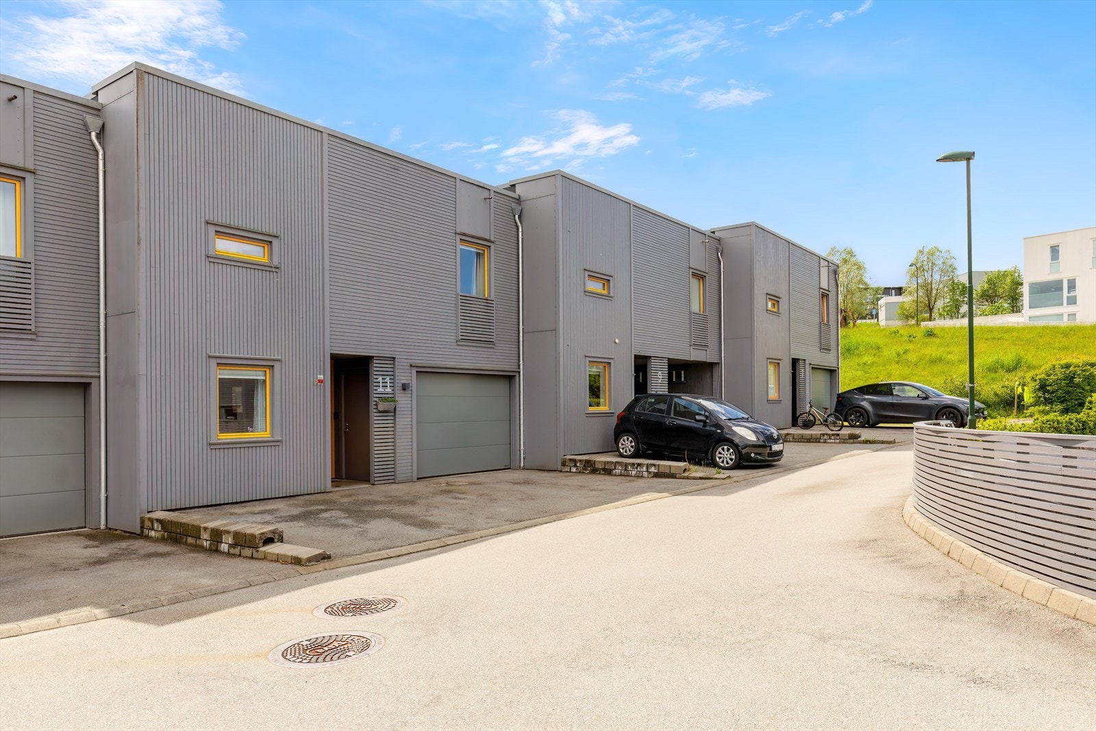 Fasade ved inngangspartiet -parkering i garasje samt plass til bil i asfaltert gårdsrom. Parkering for gjester ligger ikke langt unna boligen. Galleribilde