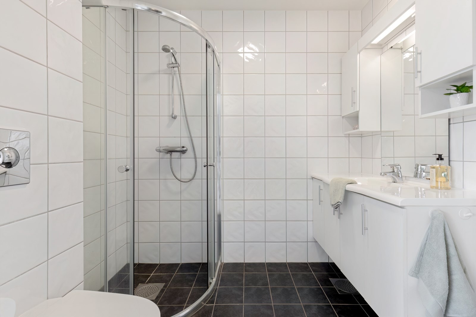 1. etg: Pent helfliset bad nr 2. Badet er innredet med vegghengt toalett, dusjhjørne og baderomsinnredning med speil. Galleribilde
