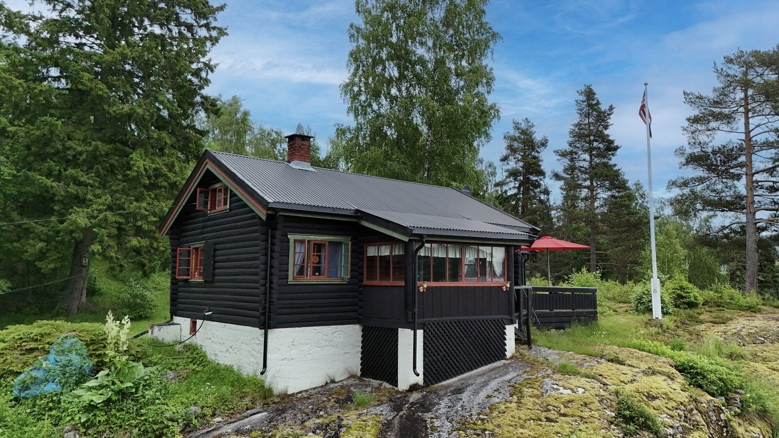 Hytta er oppført på en bergknaus med pent opparbeidet tomt med noe beplantning og naturtomt. Foto: oah-o Galleribilde