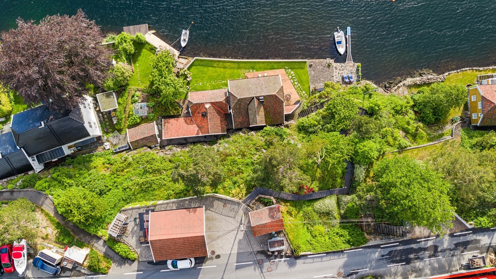 Oversiktsbilde som viser eiendommens plassering i terrenget, fra vei til sjø. Galleribilde