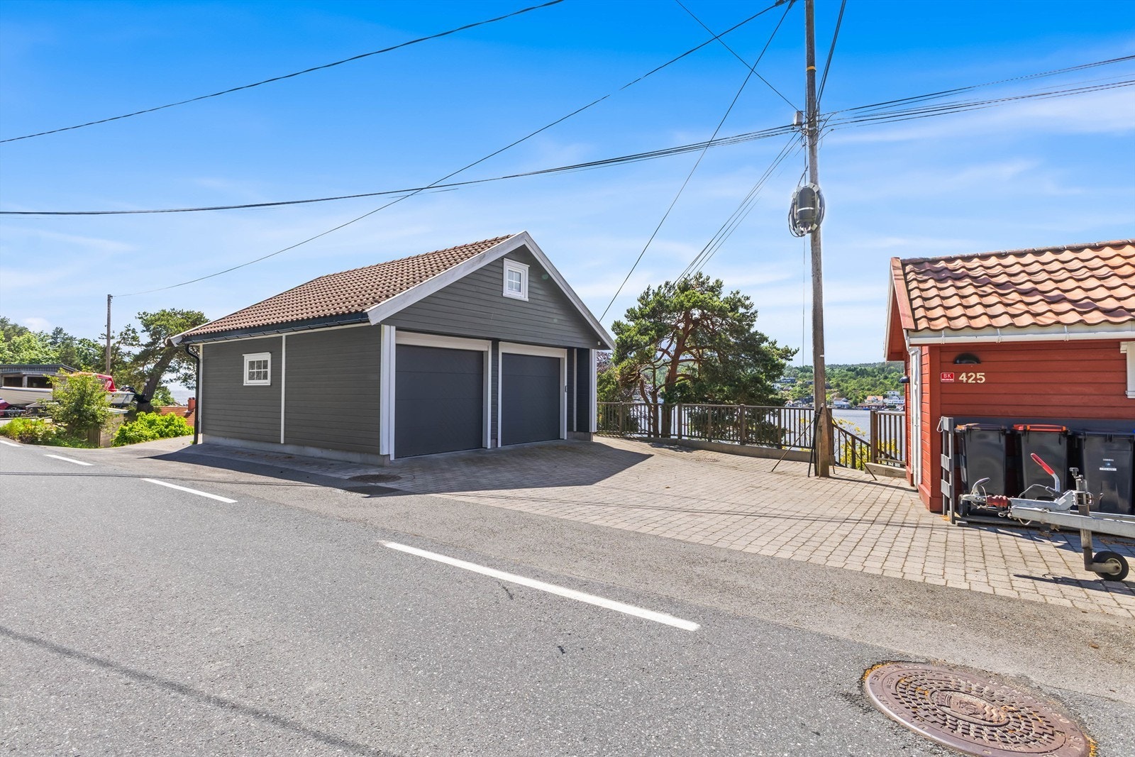 Nyere, romslig dobbelgarasje fra 2015 med innlagt strøm og elbillader. Det er også en praktisk redskapsbod som tilhører (rød) og god plass til flere biler på brostein. Galleribilde