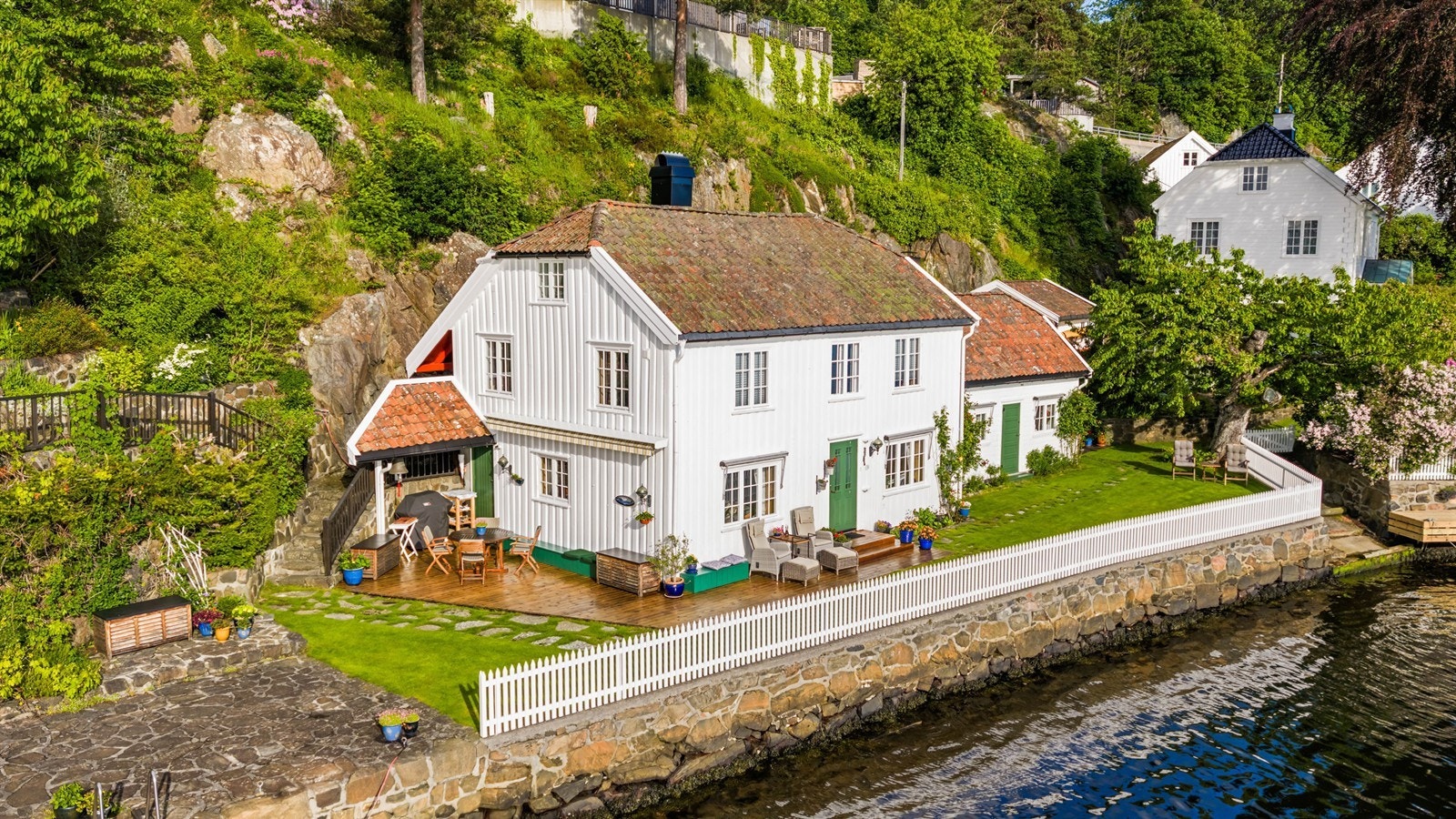 Eiendommen sett fra sjøsiden, med den karakteristiske hvite trebebyggelsen. Galleribilde