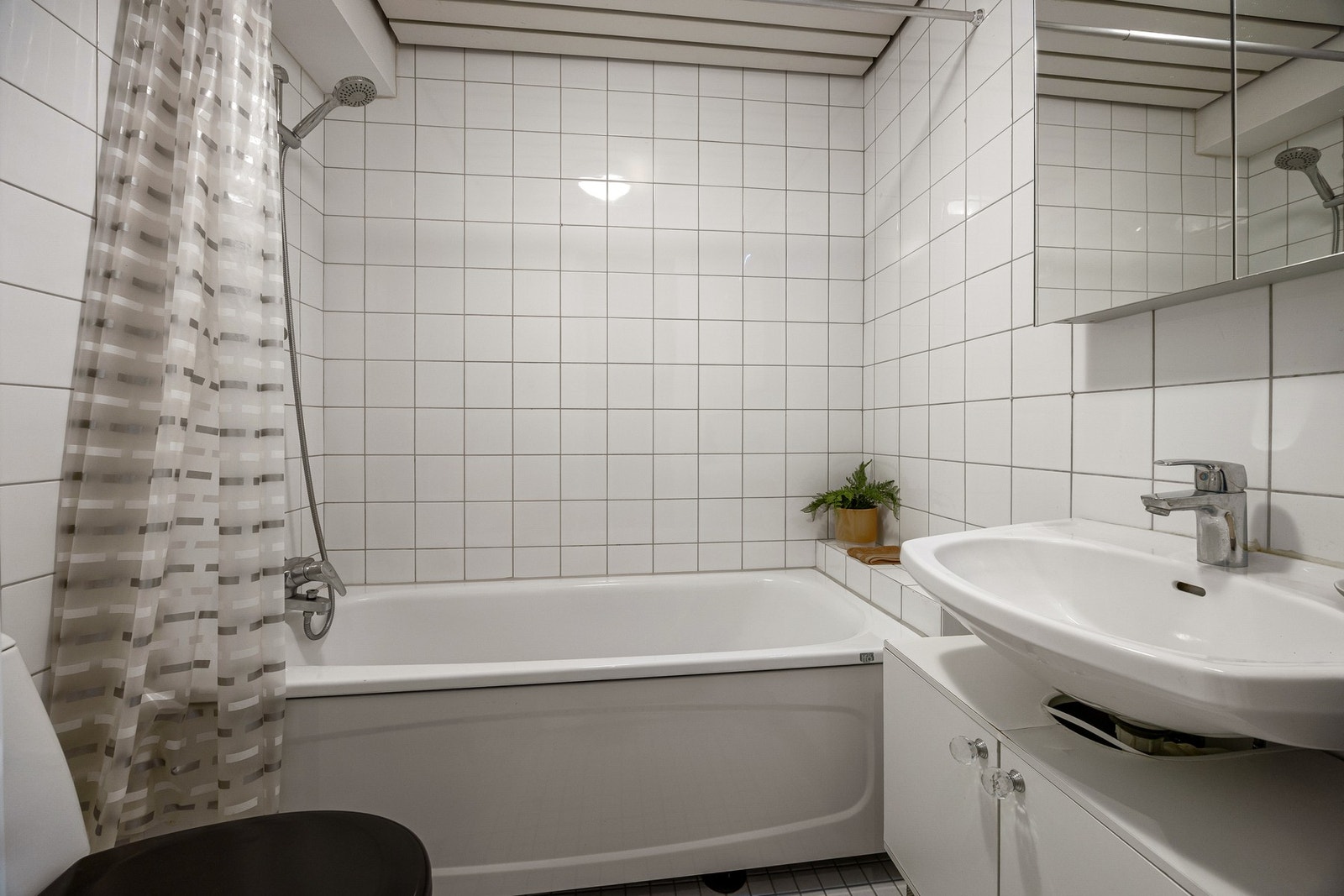 Leiligheten har et bad beliggende ved entréen. Badet har badekar, gulvstående toalett, samt servantinnredning med skapfronter. Galleribilde