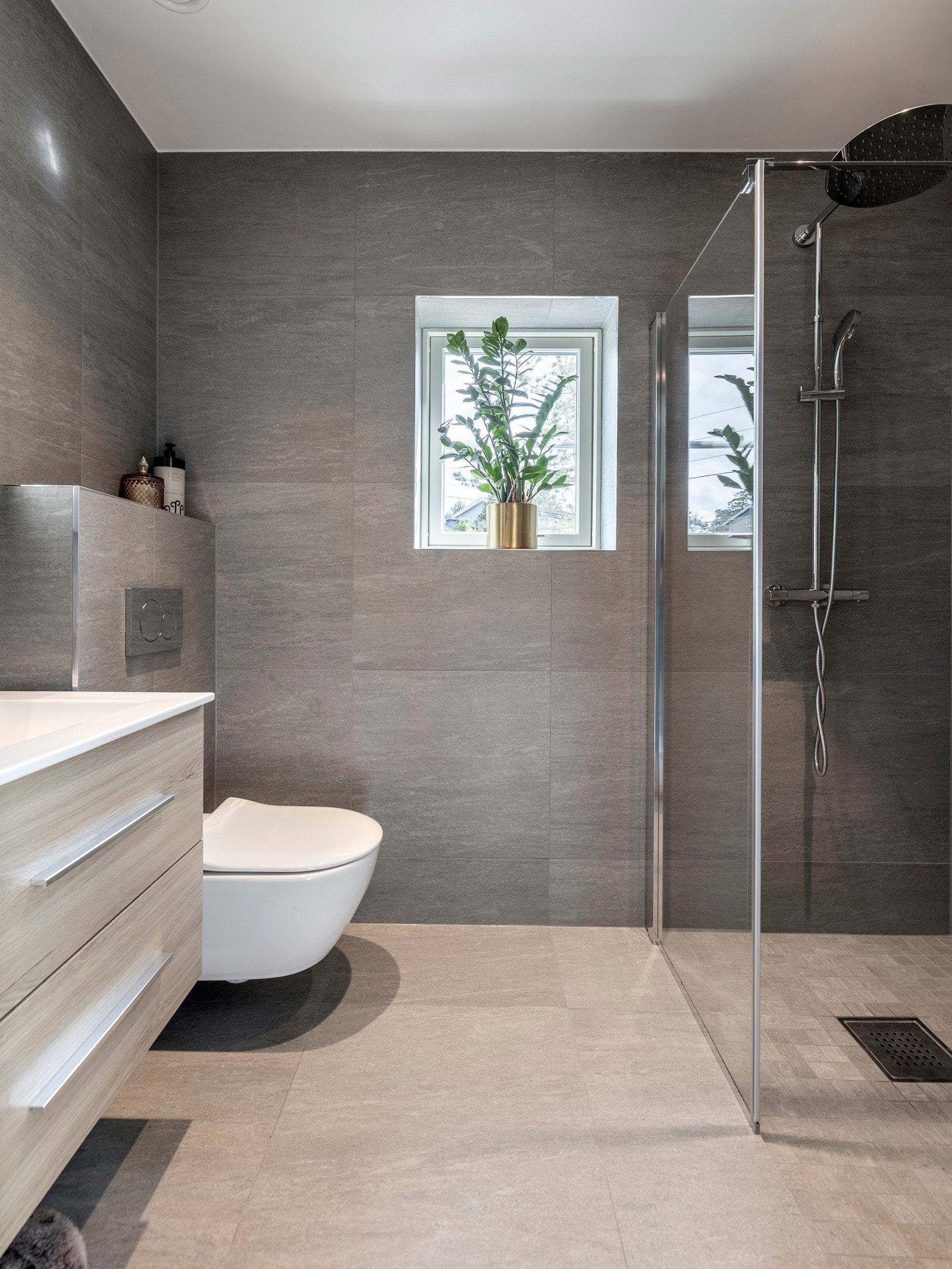 Badet i tilknytning til hovedsoverommet har et moderne og tidløst design med vegg- og gulvfliser i grå toner som skaper et elegant uttrykk. Galleribilde