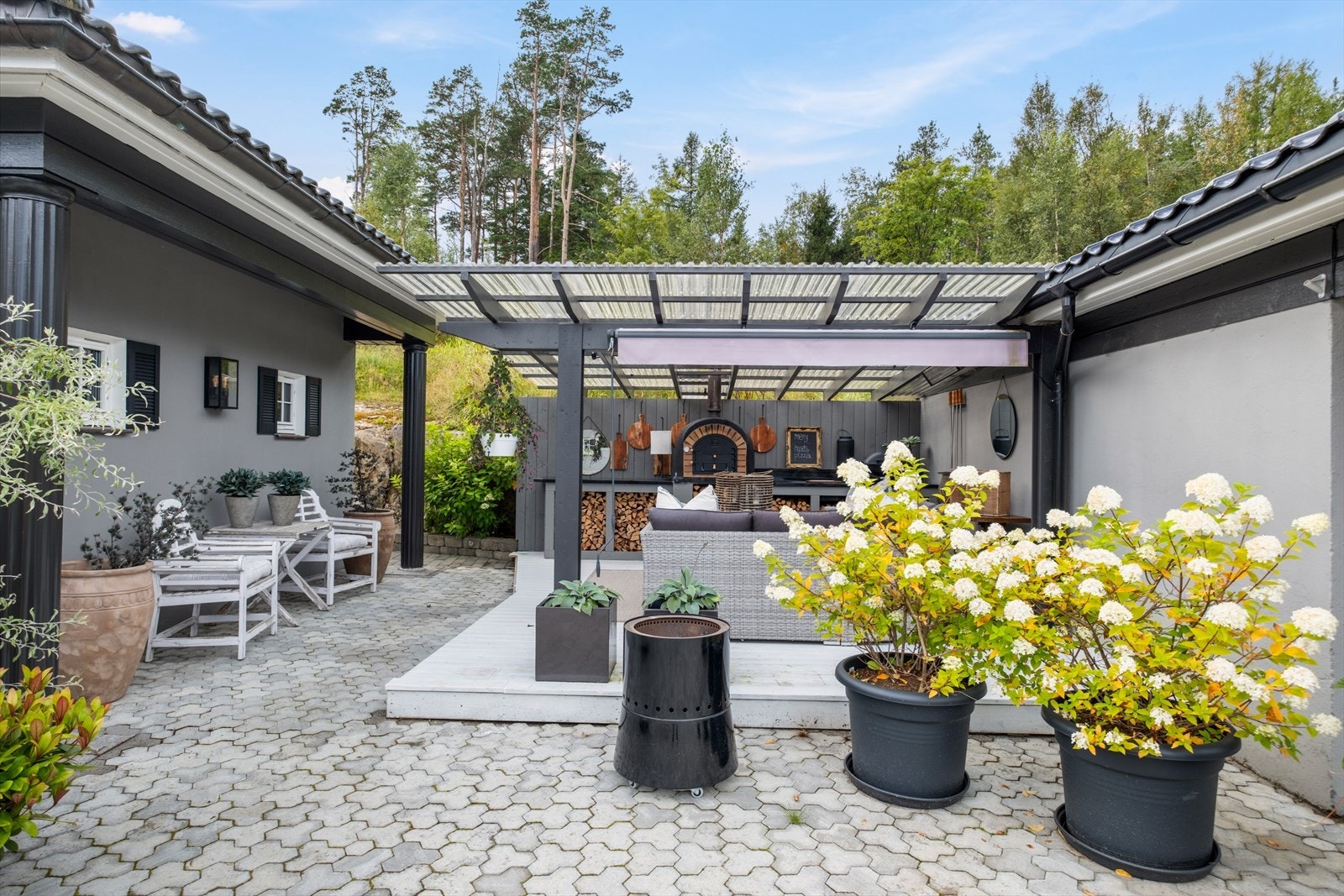 Overbygd grillplass med pizzaovn og steinbenkeplate, perfekt for sosiale sammenkomster. Galleribilde