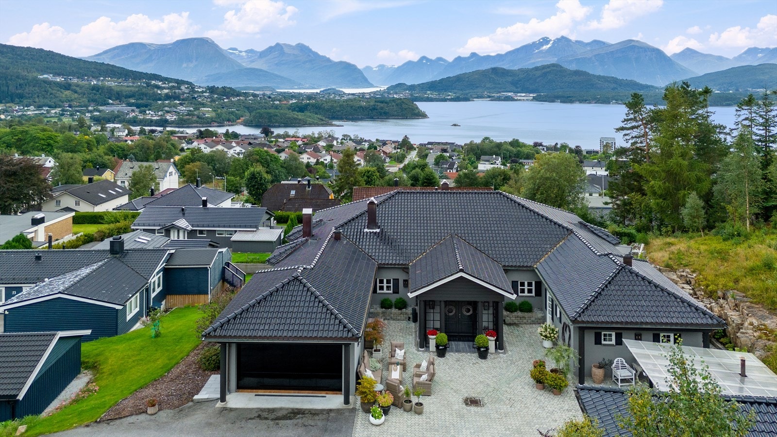 Asfaltert adkomstvei og en stor, steinbelagt gårdsplass. Galleribilde