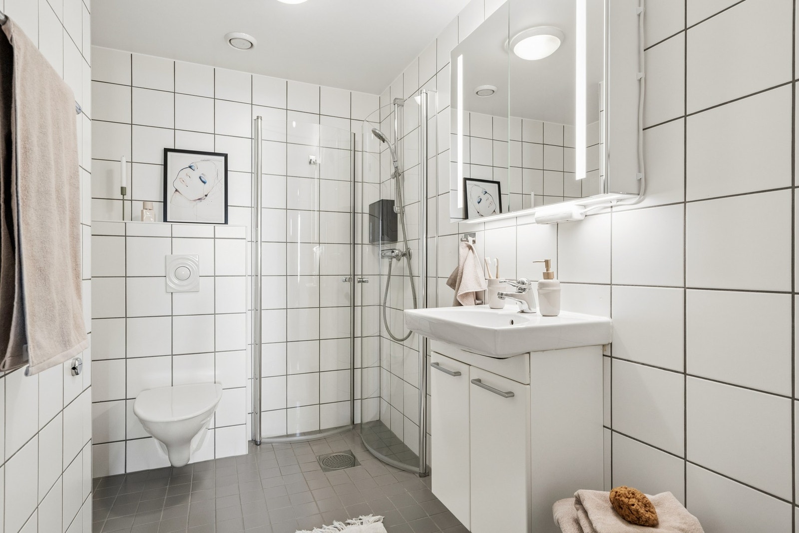 Badet har flislagt gulv med varme, vegghengt toalett og svingbare dusjvegger. Galleribilde