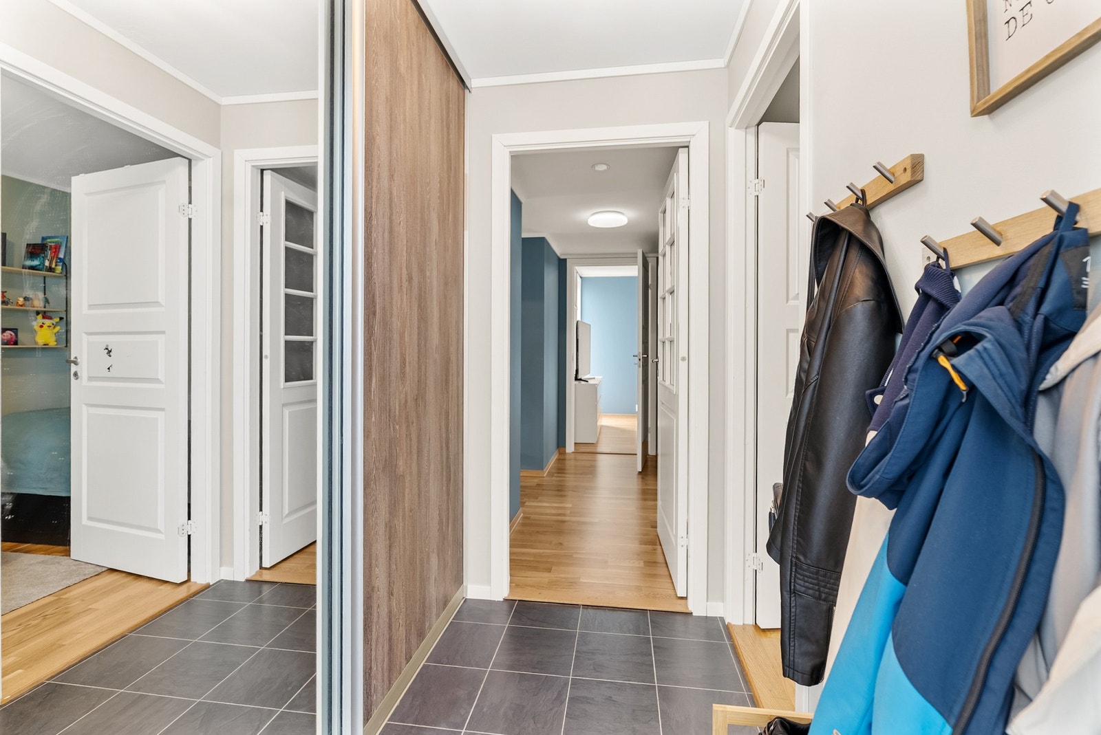 Praktisk entré med flislagt gulv og skyvedørsgarderobe med speilfronter. Galleribilde