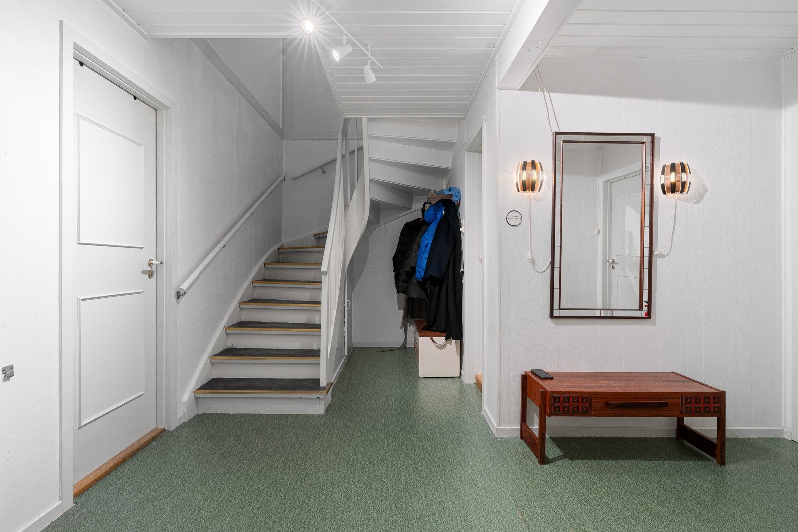Stor hall med trapp opp til hovedetasje.