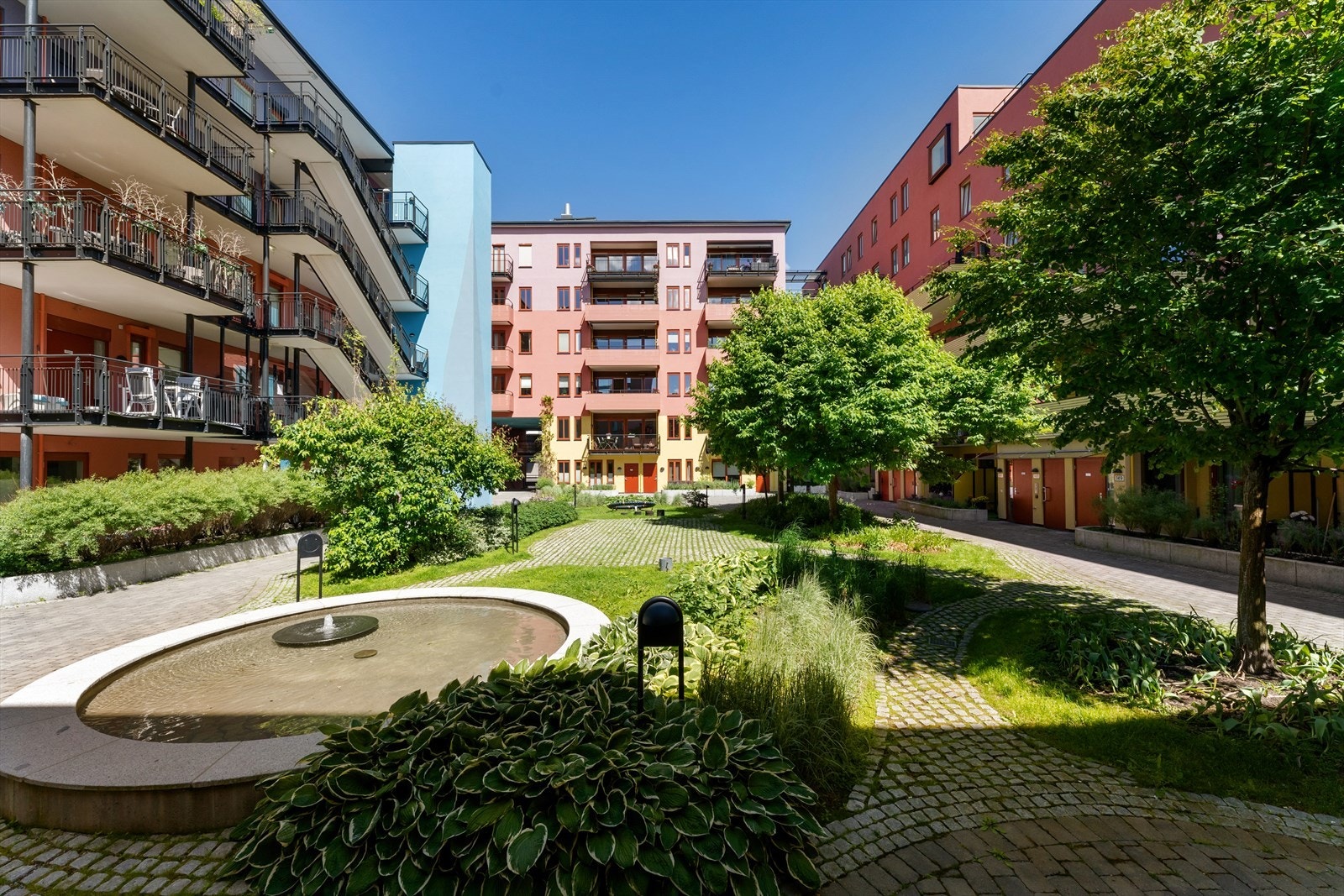 Gårdsrommet er pent opparbeidet med brostein, plen og beplantning. Galleribilde