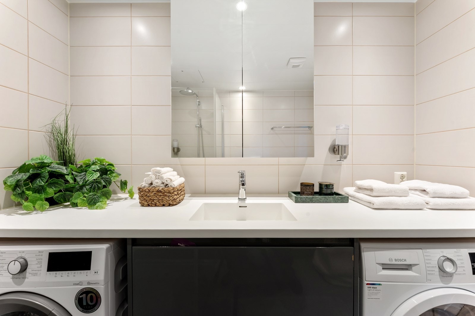 Innredning på badet består av veggmontert toalett, dusjhjørne, innfellbare glassdører og baderomsmøbel med skuffer, komposittbenkeplate og overlimt servant med ettgreps armatur fra Grohe. Utstyrt med mekanisk avtrekk og opplegg for vaskemaskin. Galleribilde