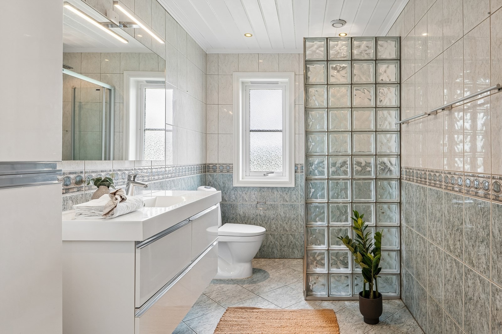 Baderom i første etasje med flislagt gulv, servantinnredning og dusjhjørne. Badet er fra huset var nytt i 2001. Galleribilde