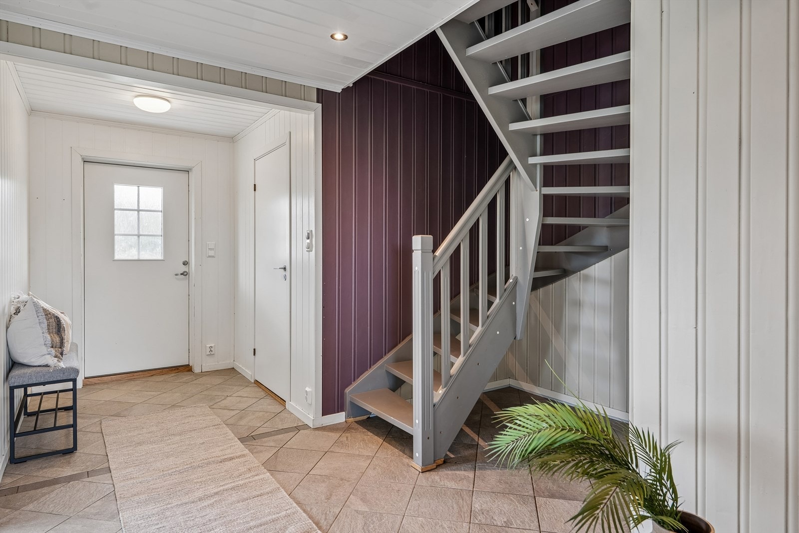 Romslig entré med flislagt gulv og trapp som leder opp til loftsetasjen. Inngang til en praktisk bod fra entréen. Galleribilde