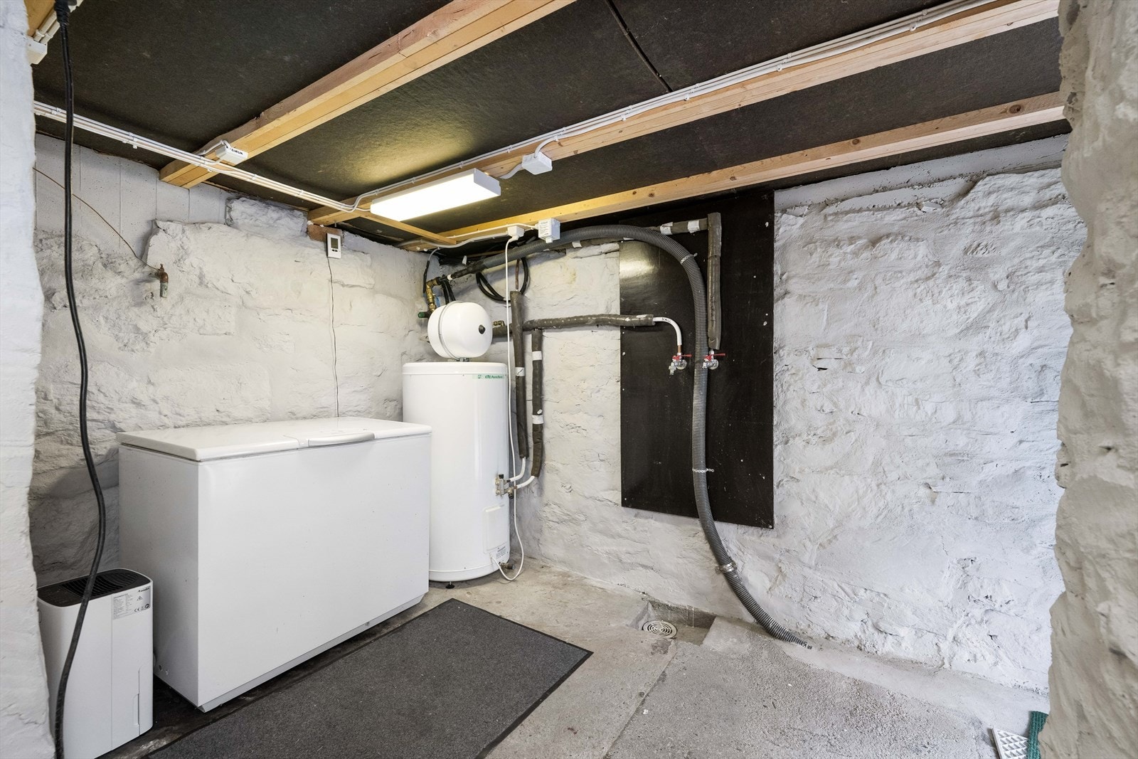 jelleren er uinnredet med synlig grunnmur og betonggulv mot grunn. Her er varmtvannstanken på 194 liter fra 2007 plassert. Galleribilde