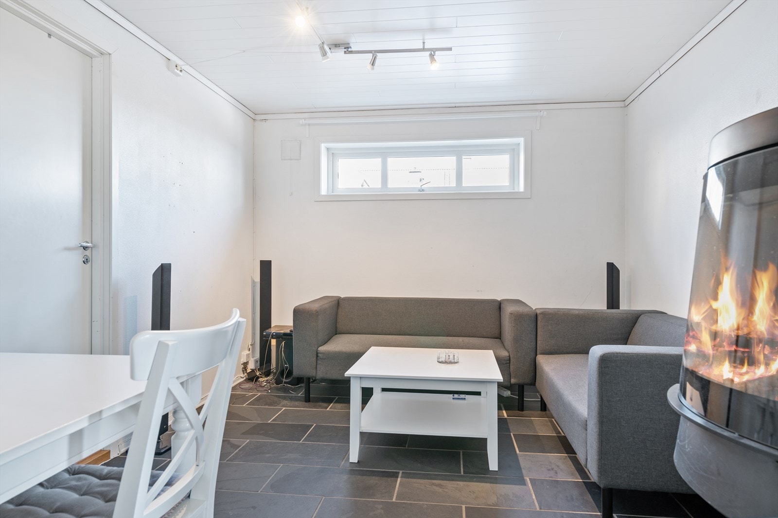 Stuen har en frittstående vedovn med glassdør og plass til sofagruppe og spisebord. Galleribilde