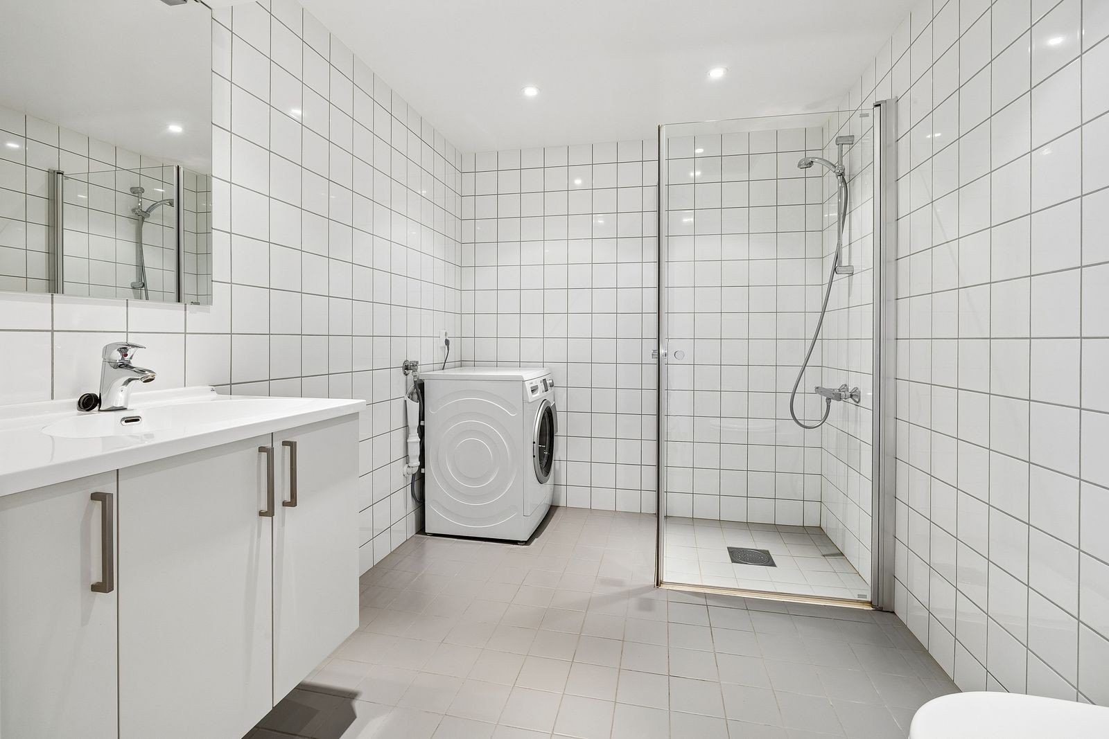Pent flislagt bad med dusjnisje, wc, servant og vaskemaskin. Galleribilde