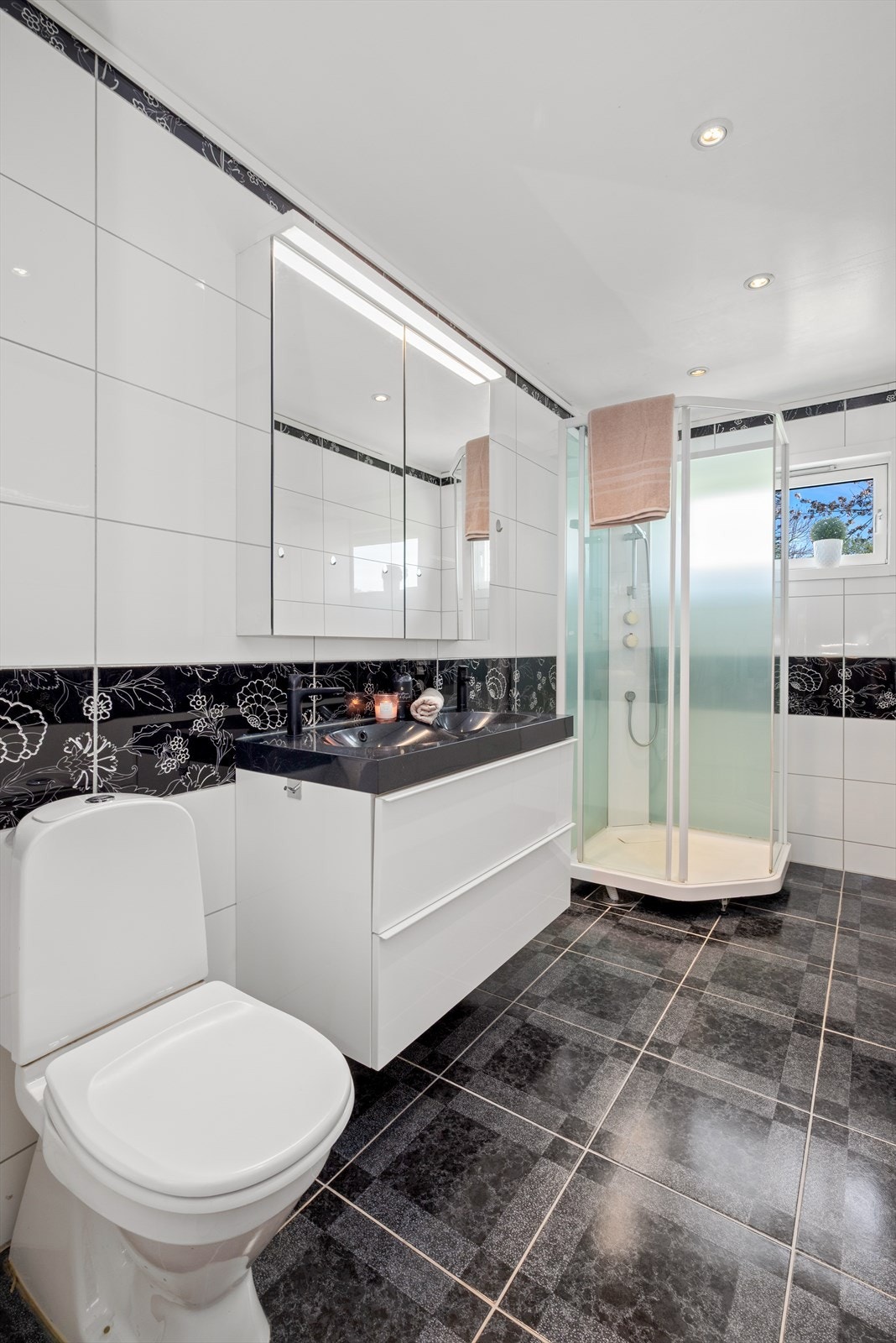 Videre finner vi etasjens bad, som byr på flis på gulv og vegger. Malt overflate i himling og gulvvarme. Badet er utstyrt med dusjkabinett, servantskap, wc og opplegg for vaskemaskin. Galleribilde