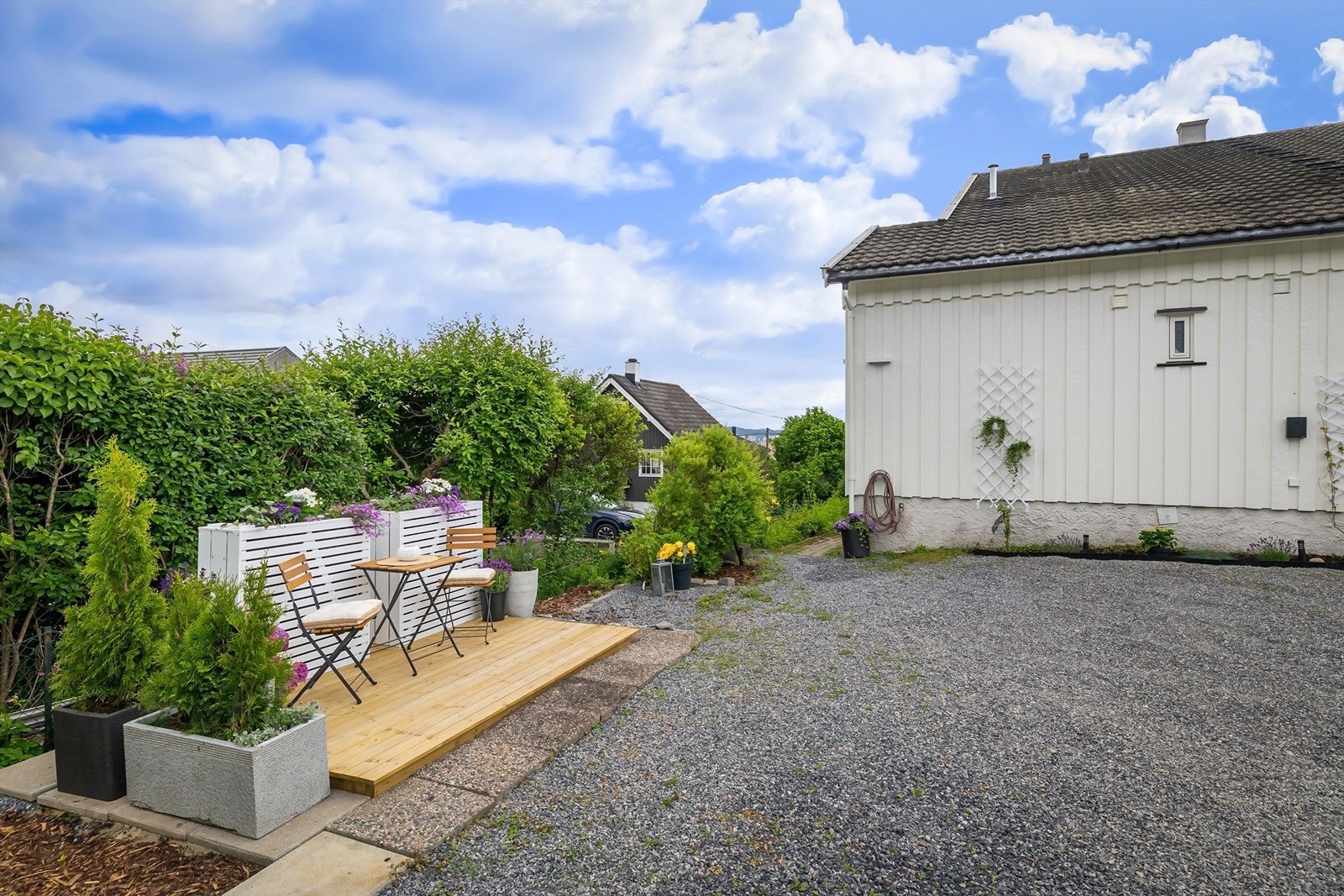 Romslig gårdsplass hvor hver seksjon har én biloppstillingsplass lags husveggen Galleribilde
