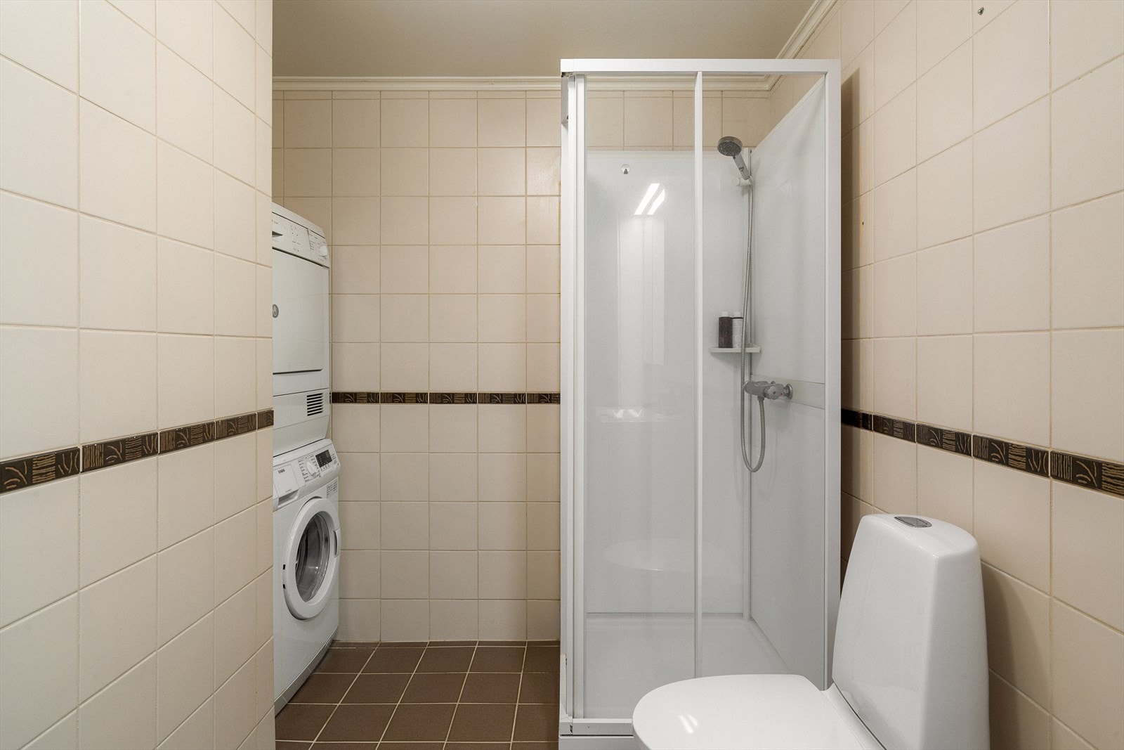 Badet er praktisk innredet med dusjkabinett og opplegg for vaskesøyle. Galleribilde