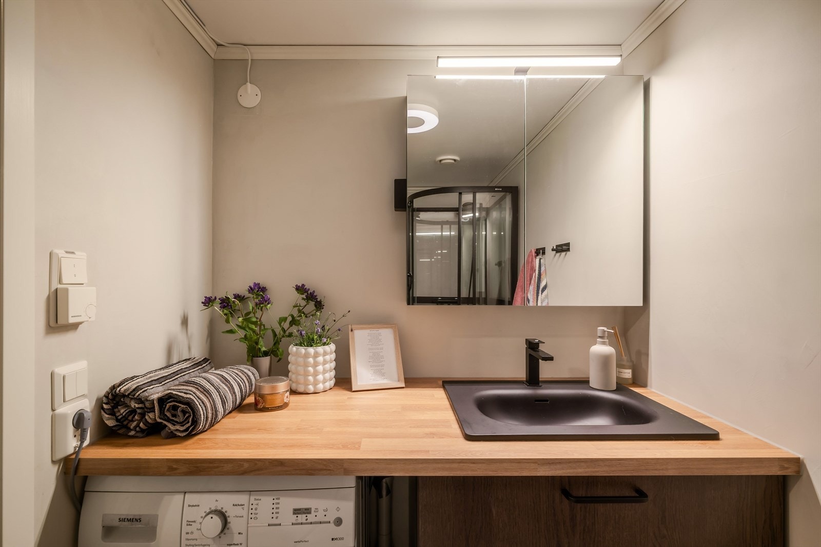Badet har benkeplate med sort servant, innredning med 2 skuffer og et praktisk speilskap samt opplegg for vaskemaskin. Galleribilde