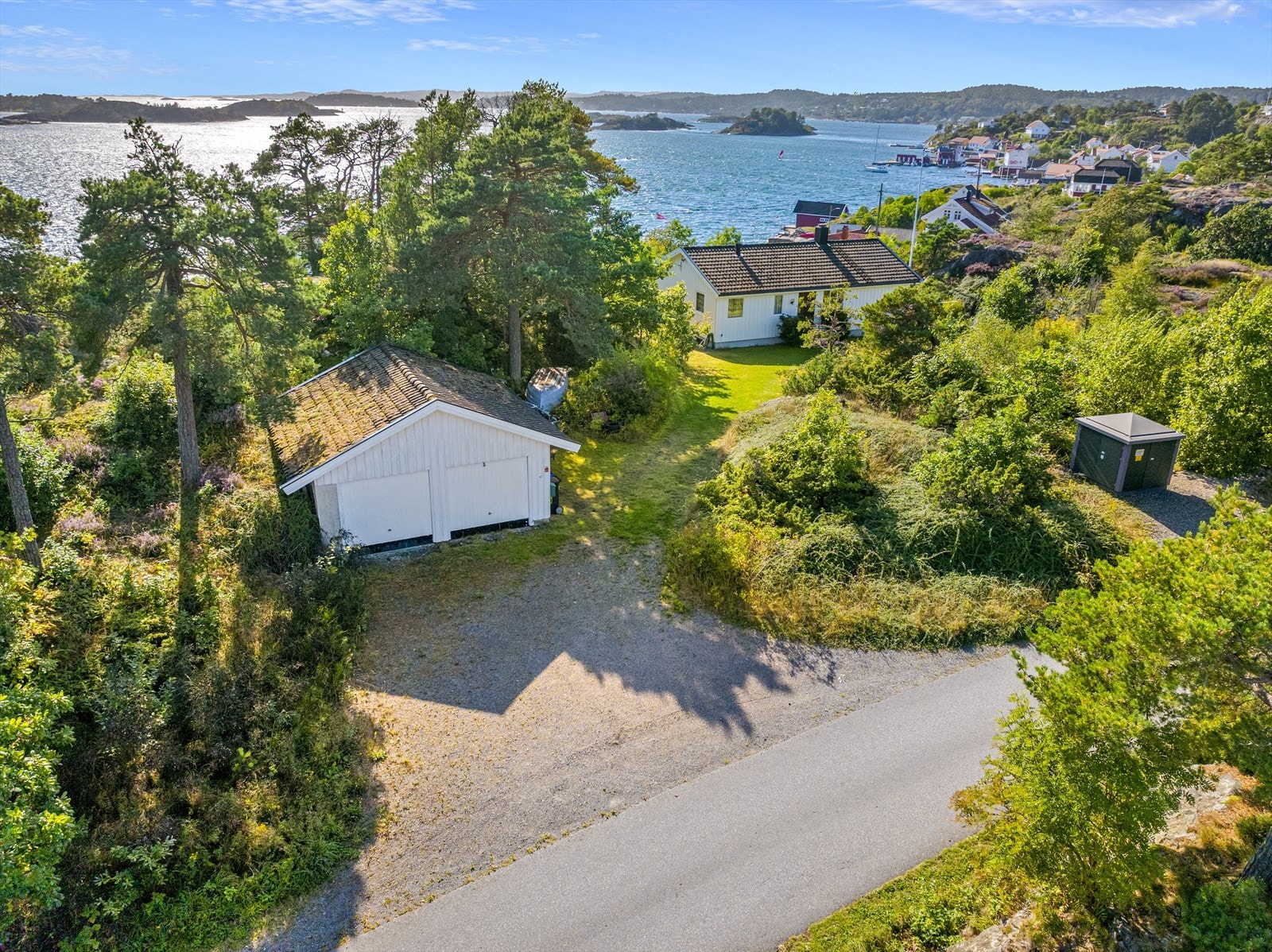 Garasje ved innkjørsel. I forbindelse med salget vil det bli fradelt parsell mot øst (ca. 1350 m2), jfr. kartskisse i salgsprospekt (til venstre for garasjen, se vedlagte kart). Galleribilde