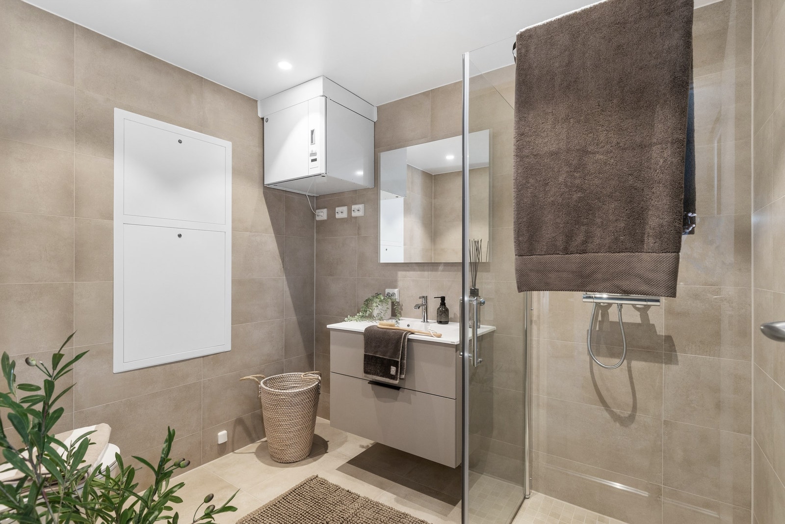 Badet er utstyrt med moderne baderomsinnredning, vegghengt toalett og dusjhjørne med glassdører. Galleribilde