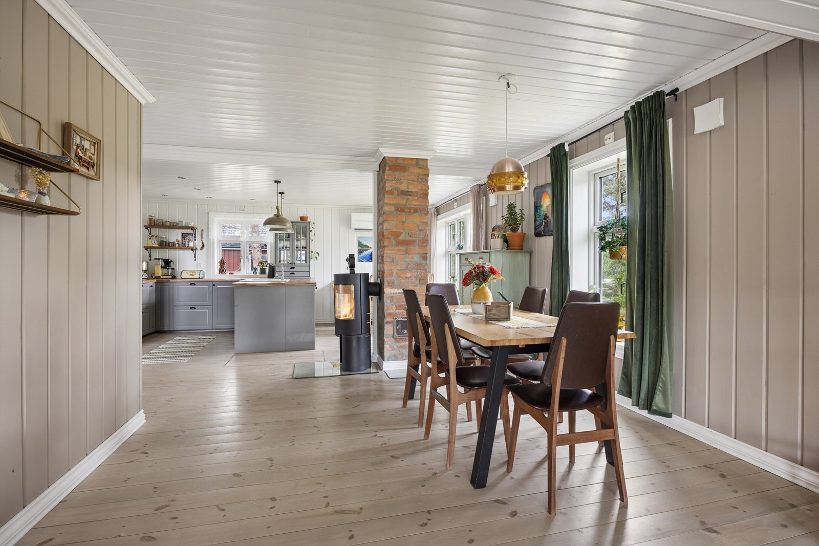 Spisestuen ligger i åpen forbindelse med kjøkkenet, med en mursteinspipe som en rustikk detalj. Galleribilde