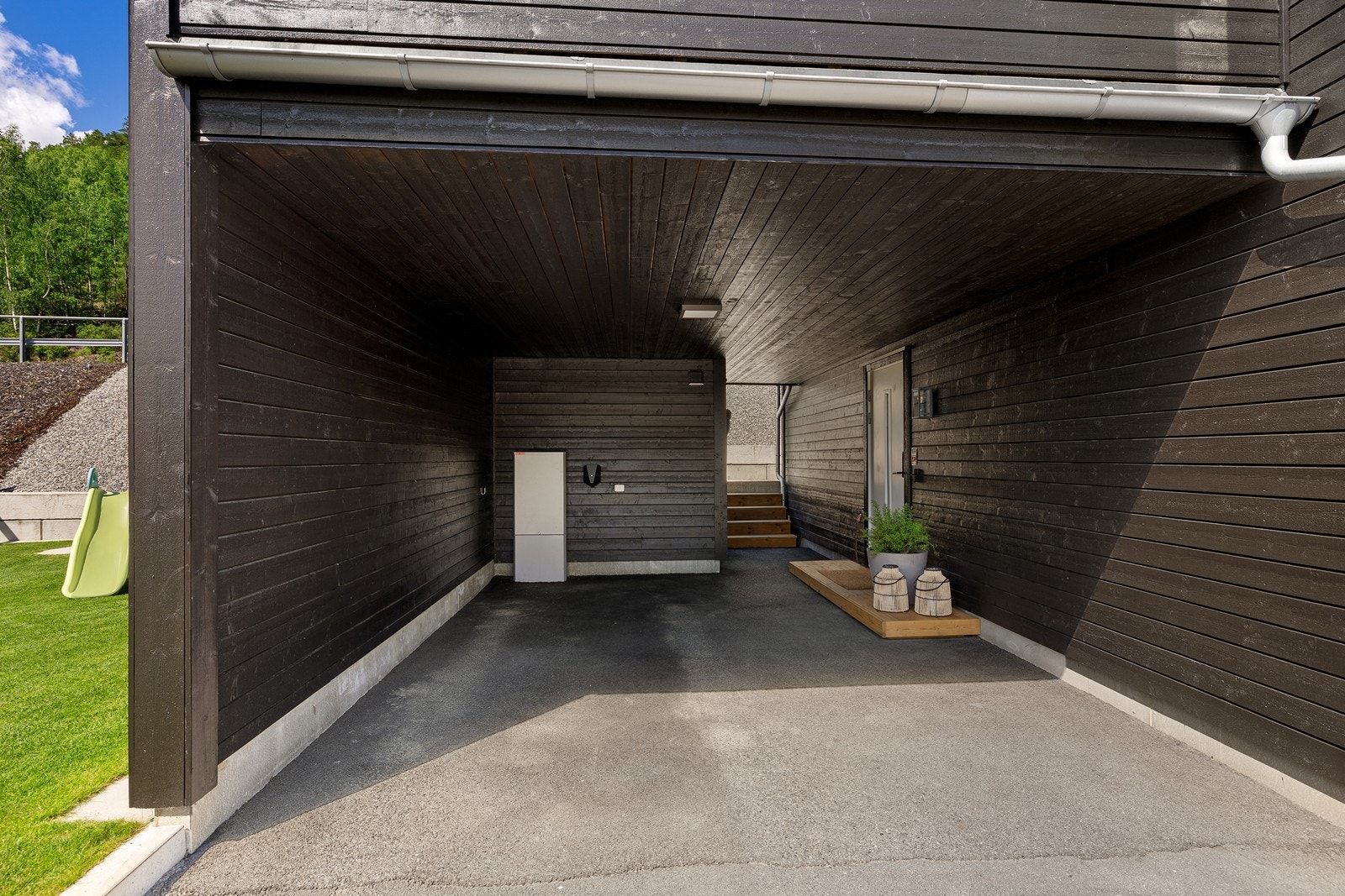Overbygget inngangsparti med carport og direkte adkomst til en delvis isolert utebod. Galleribilde